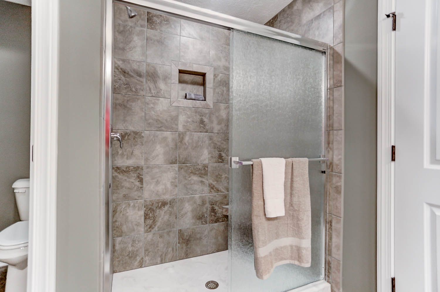 A bathroom with a walk in shower and a toilet.