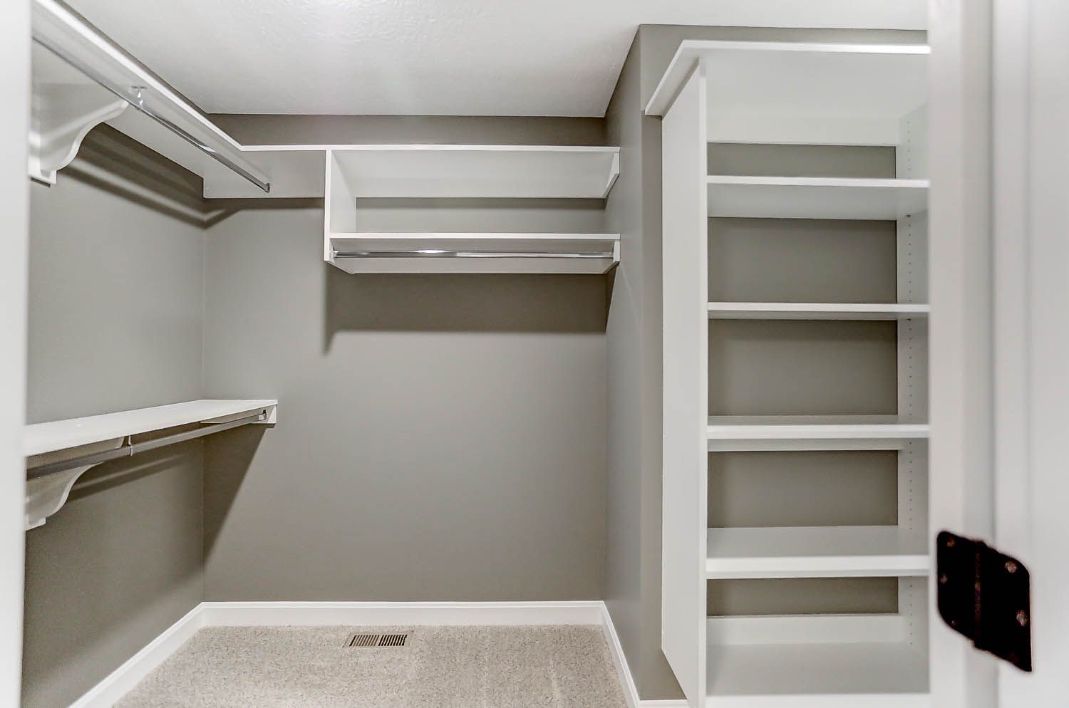 A walk in closet with a lot of shelves and a door.