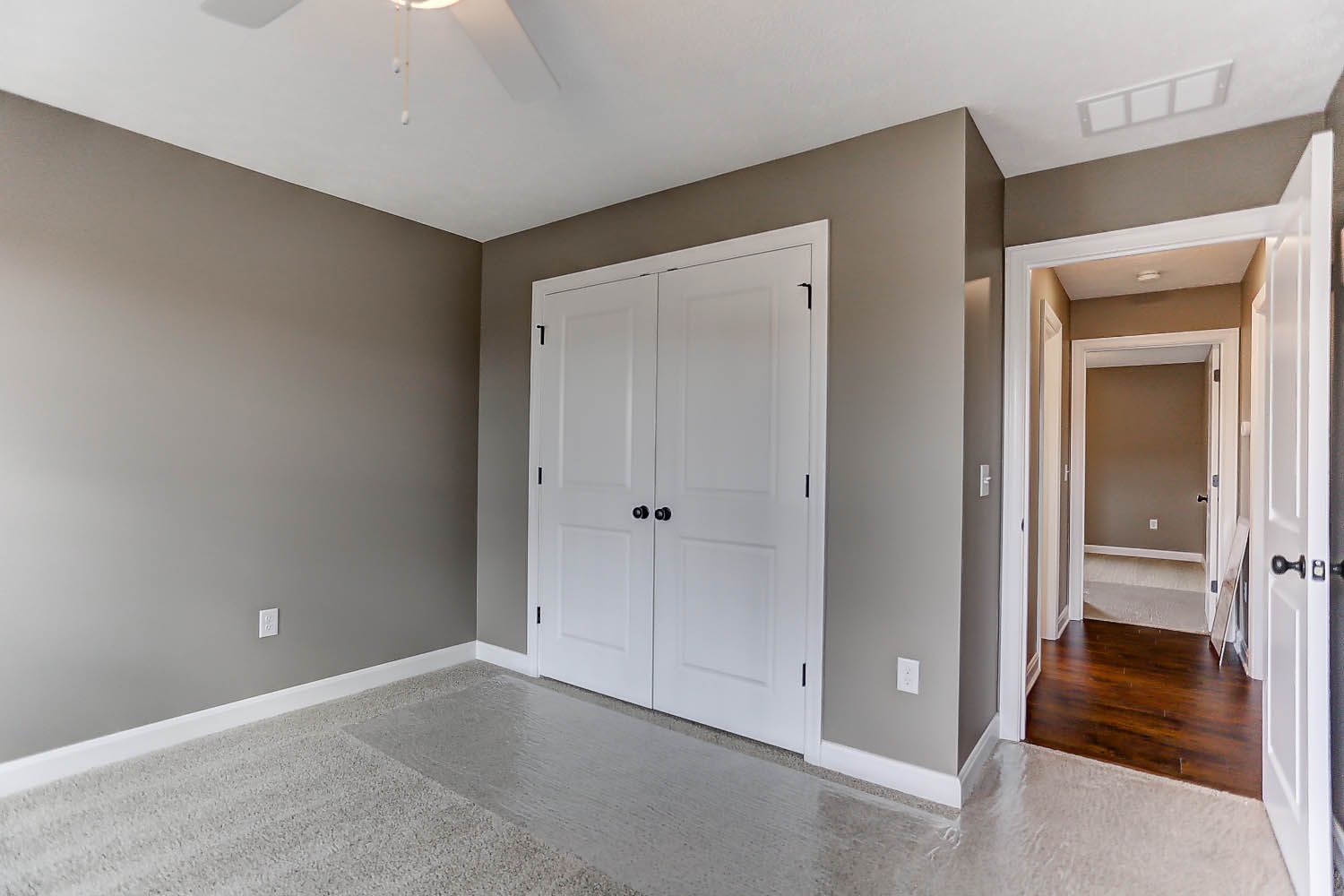 An empty bedroom with a large closet and a ceiling fan.