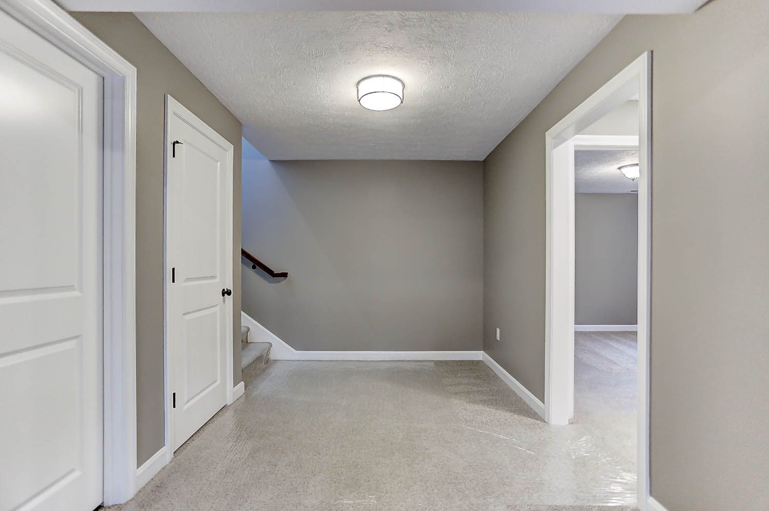 A hallway in a house with a staircase and a light on the ceiling.