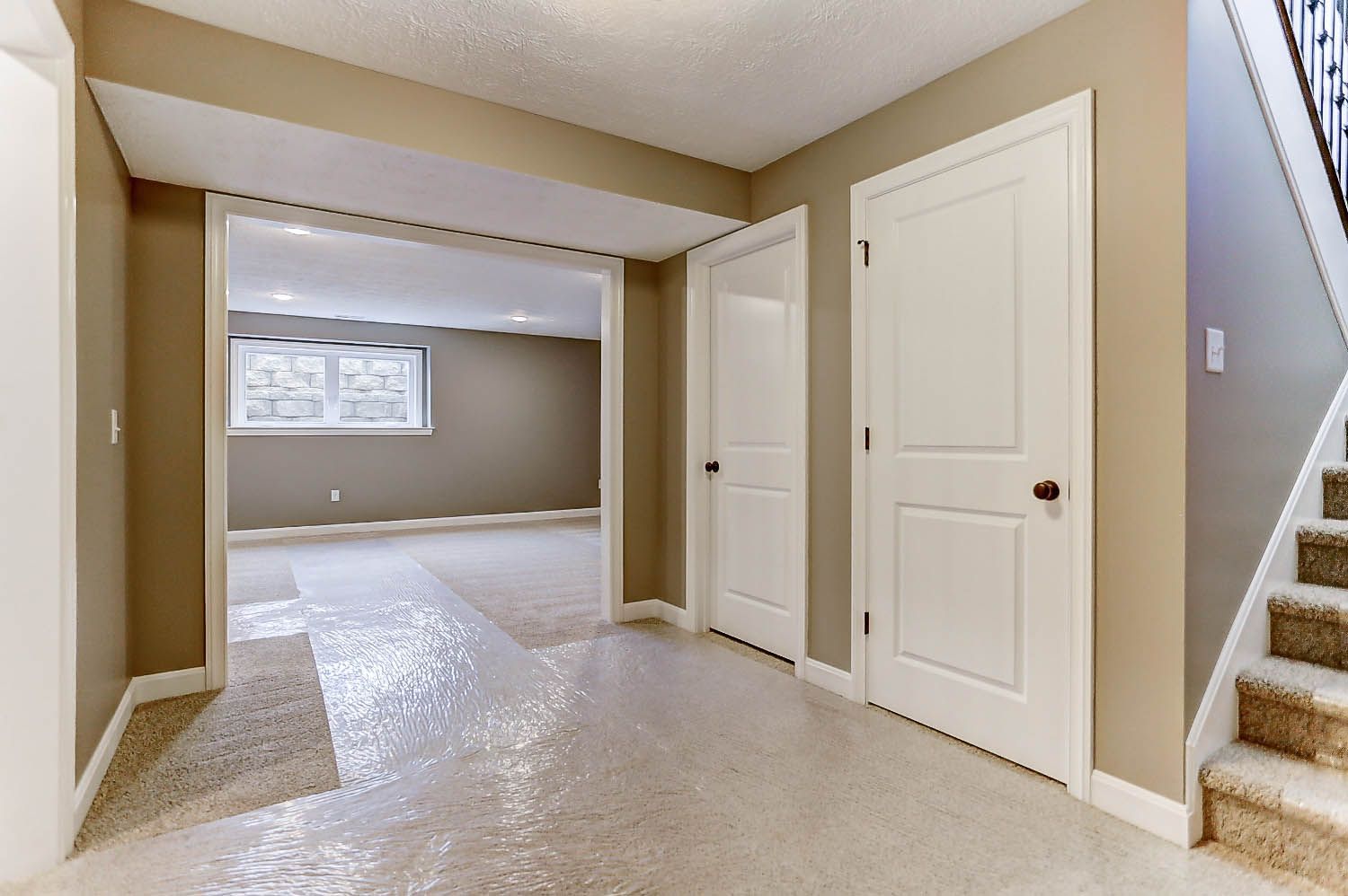 An empty basement with stairs leading up to the second floor.