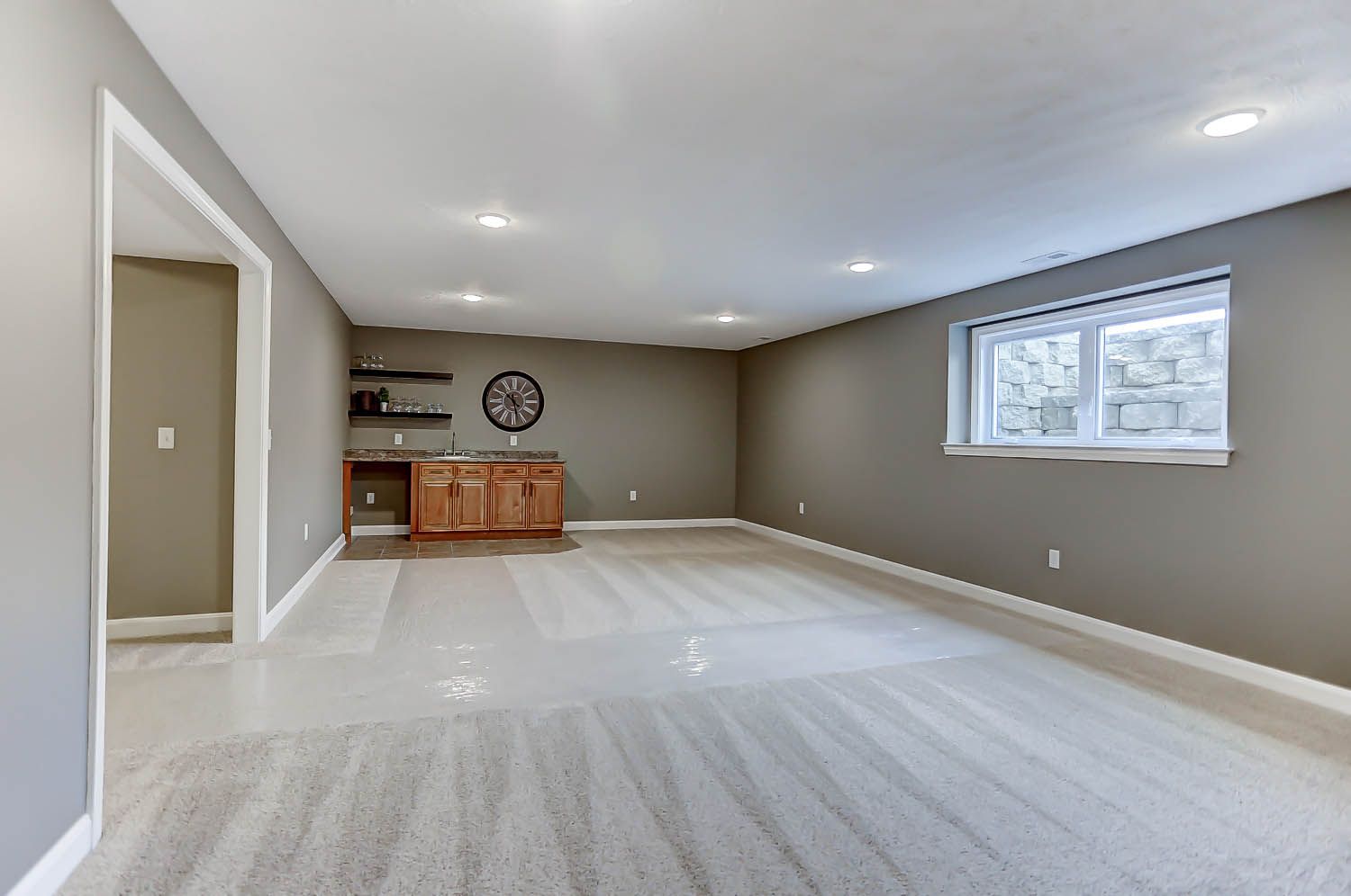 An empty basement with a bar and a clock on the wall.