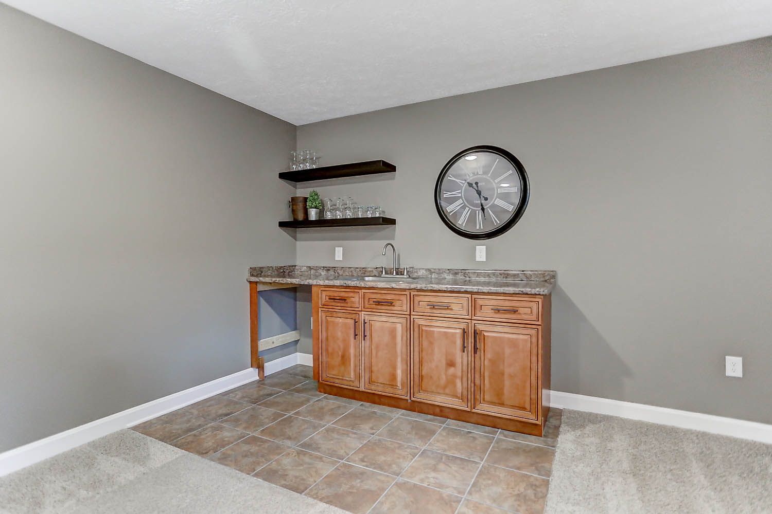 A kitchen with a sink and a clock on the wall.