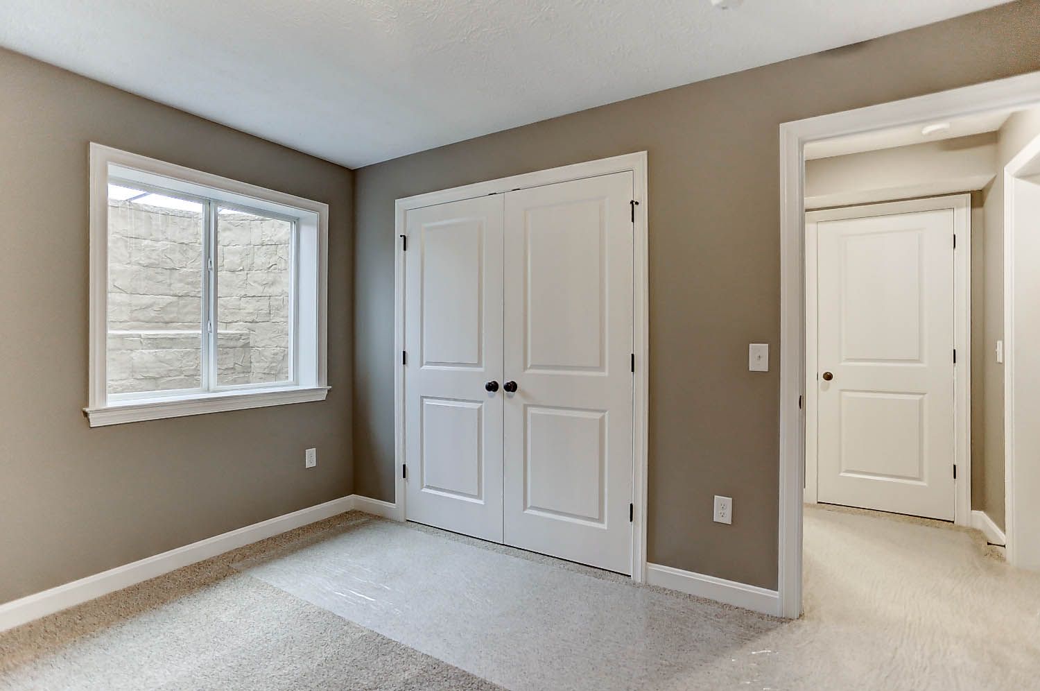 An empty room with a window and a closet.