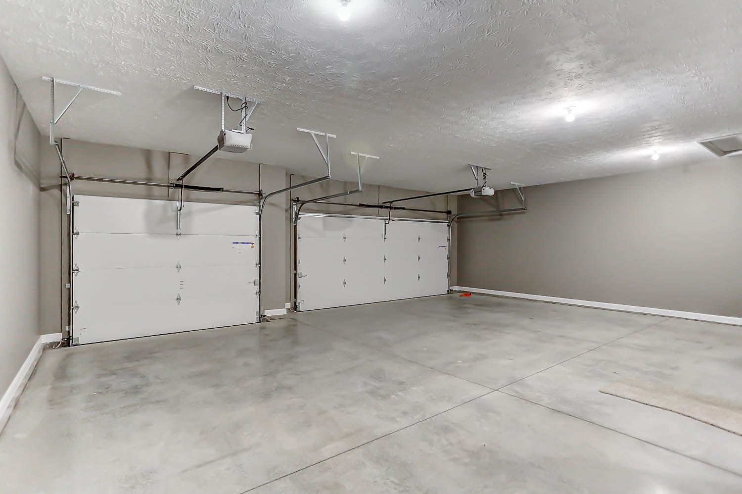 An empty garage with two garage doors and a ceiling fan.