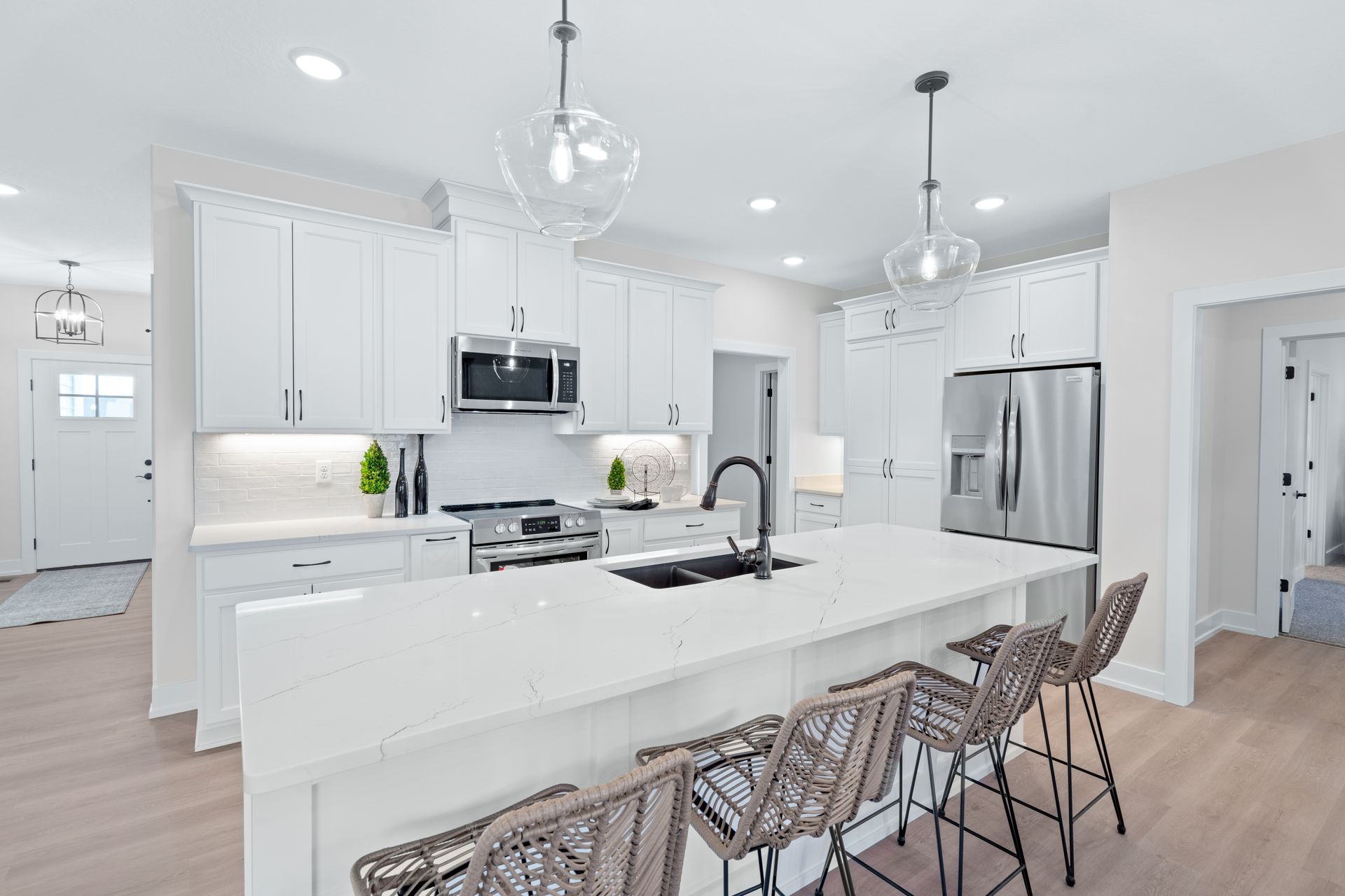 A kitchen with white cabinets , stainless steel appliances , and a large island.