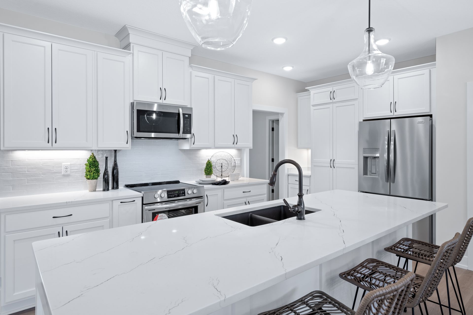 A kitchen with white cabinets , stainless steel appliances , and a large island.