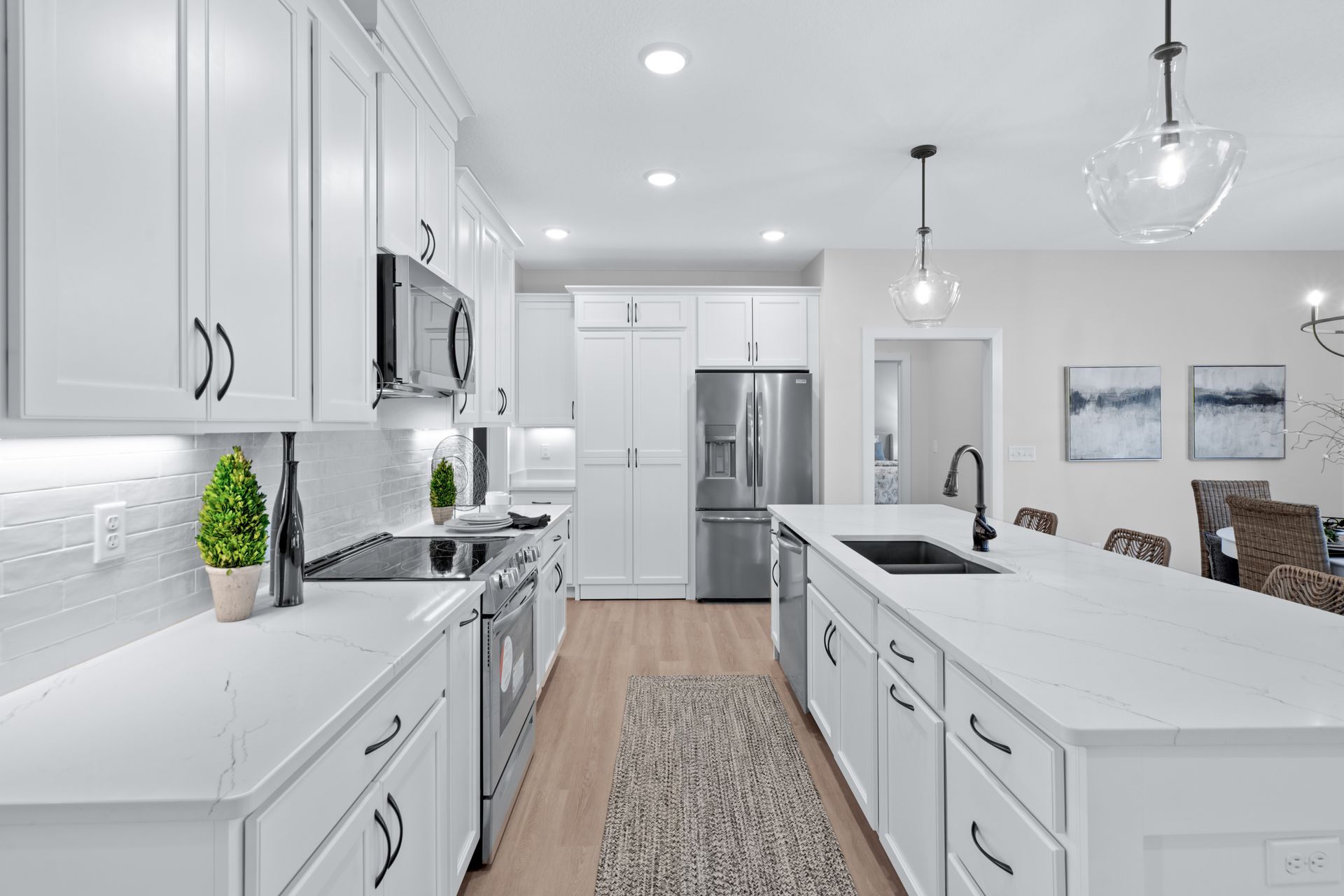 A kitchen with white cabinets , stainless steel appliances , and a large island.