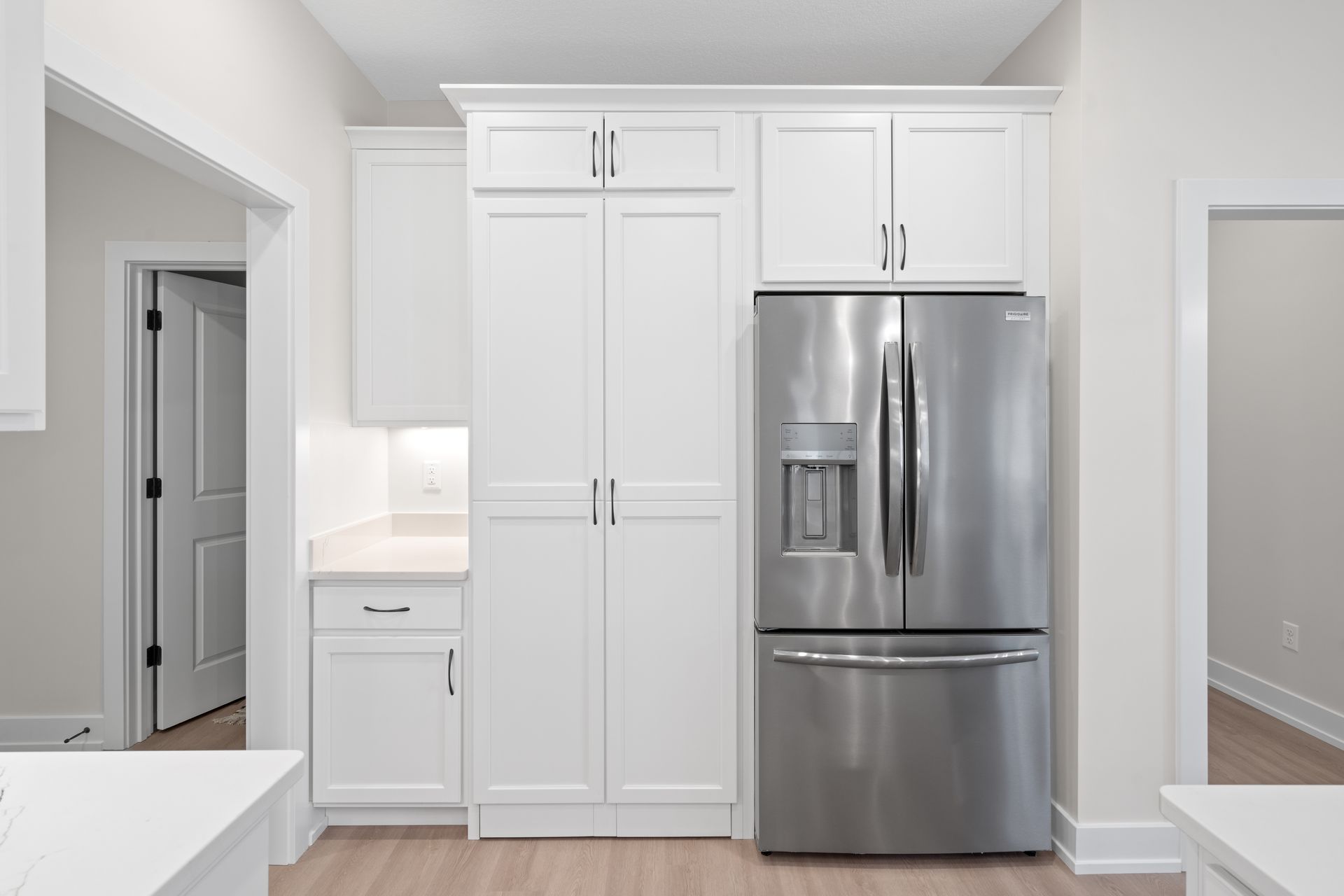 A kitchen with white cabinets and a stainless steel refrigerator.