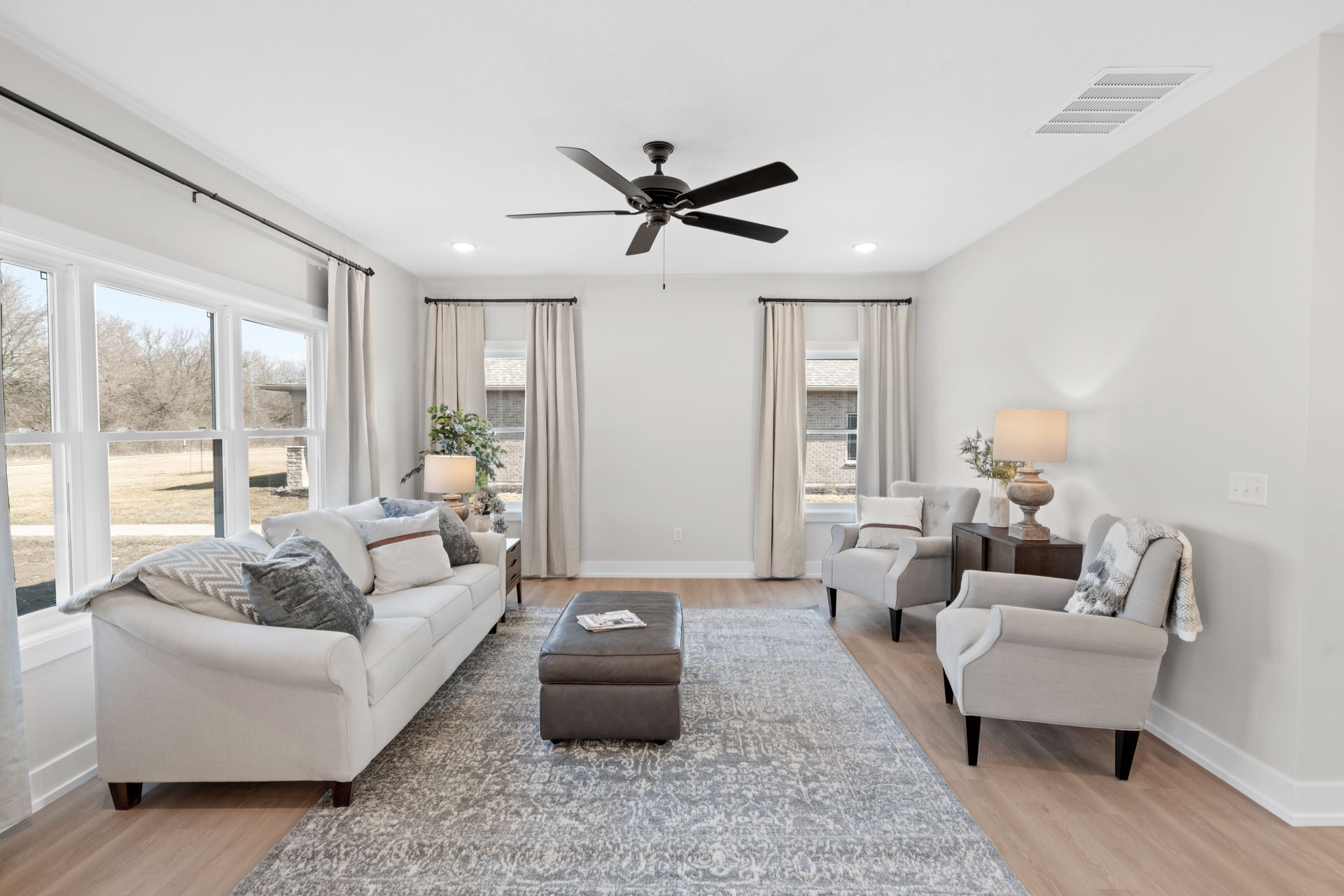 A living room with a couch , chairs , and a ceiling fan.