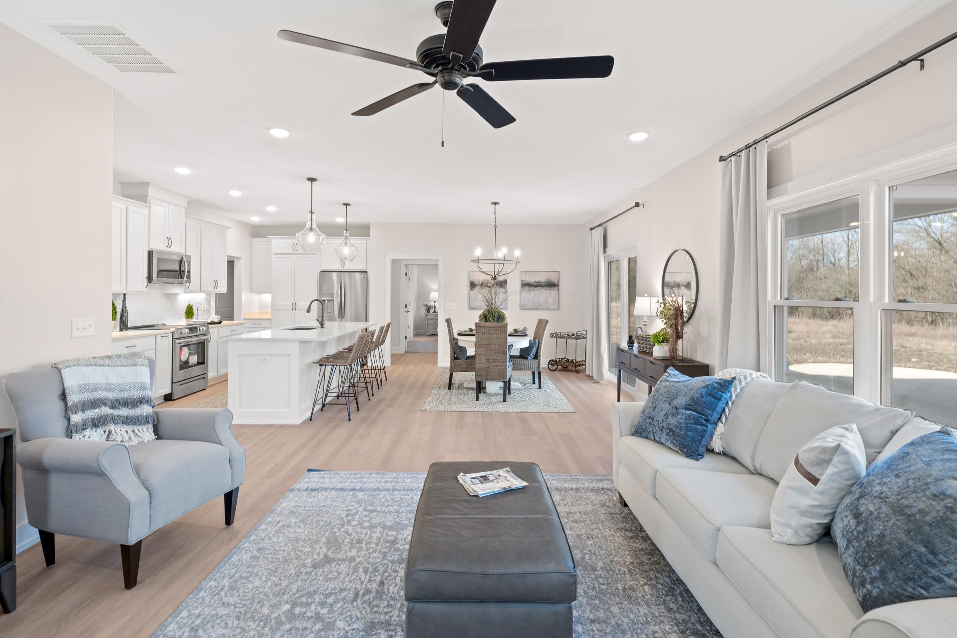 A living room with a couch , chairs , and a ceiling fan.