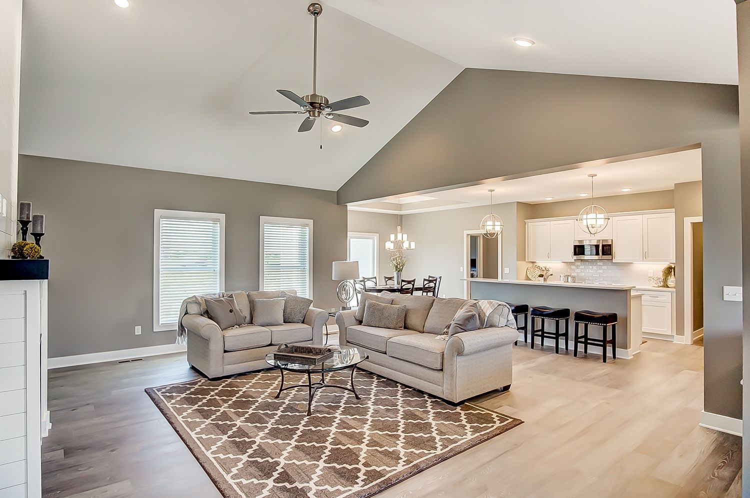 A living room with two couches , a rug and a ceiling fan.