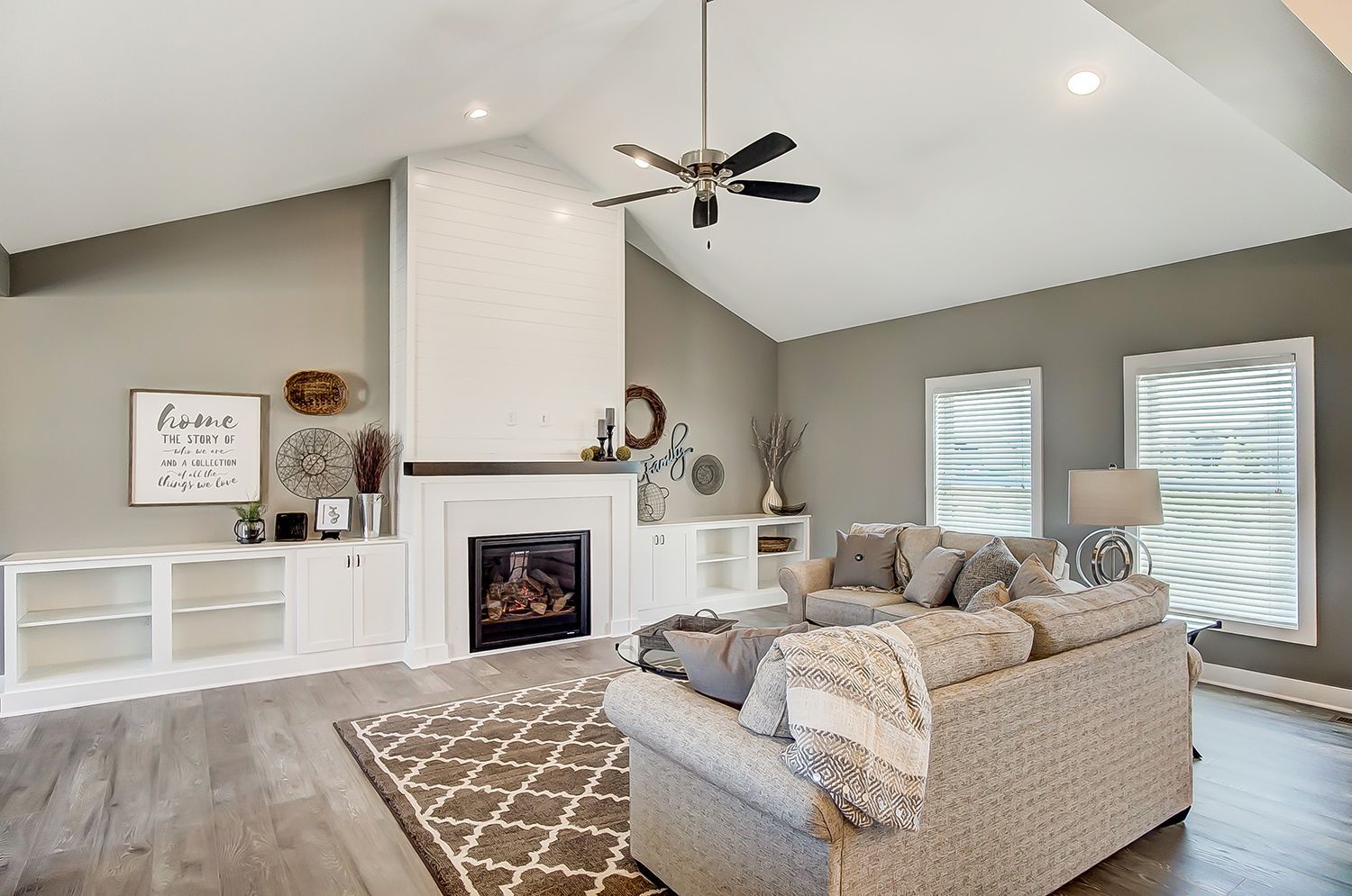 A living room with a couch , fireplace and ceiling fan.