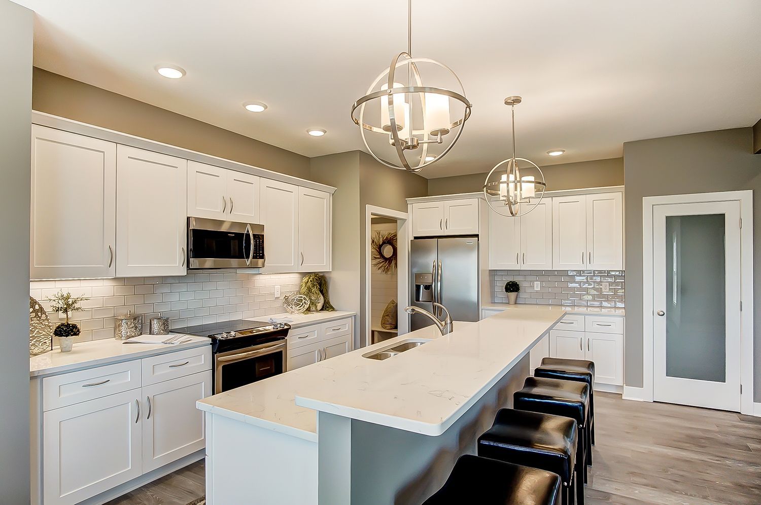 A kitchen with white cabinets , stainless steel appliances , and a large island.