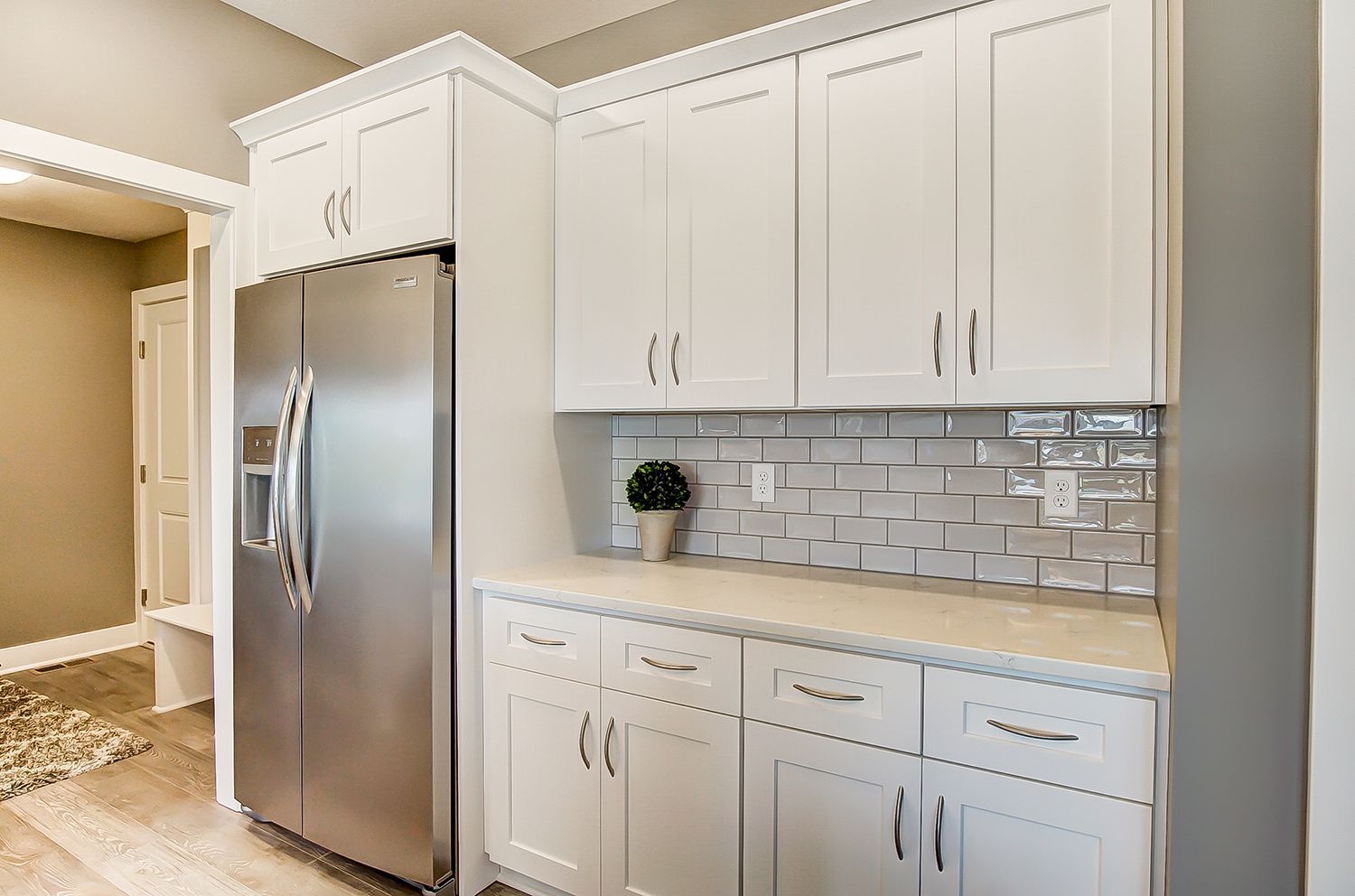 A kitchen with white cabinets and a stainless steel refrigerator.