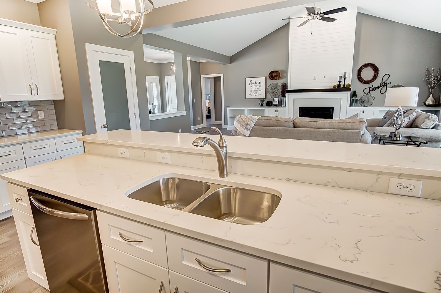 A kitchen with a stainless steel sink and white cabinets.