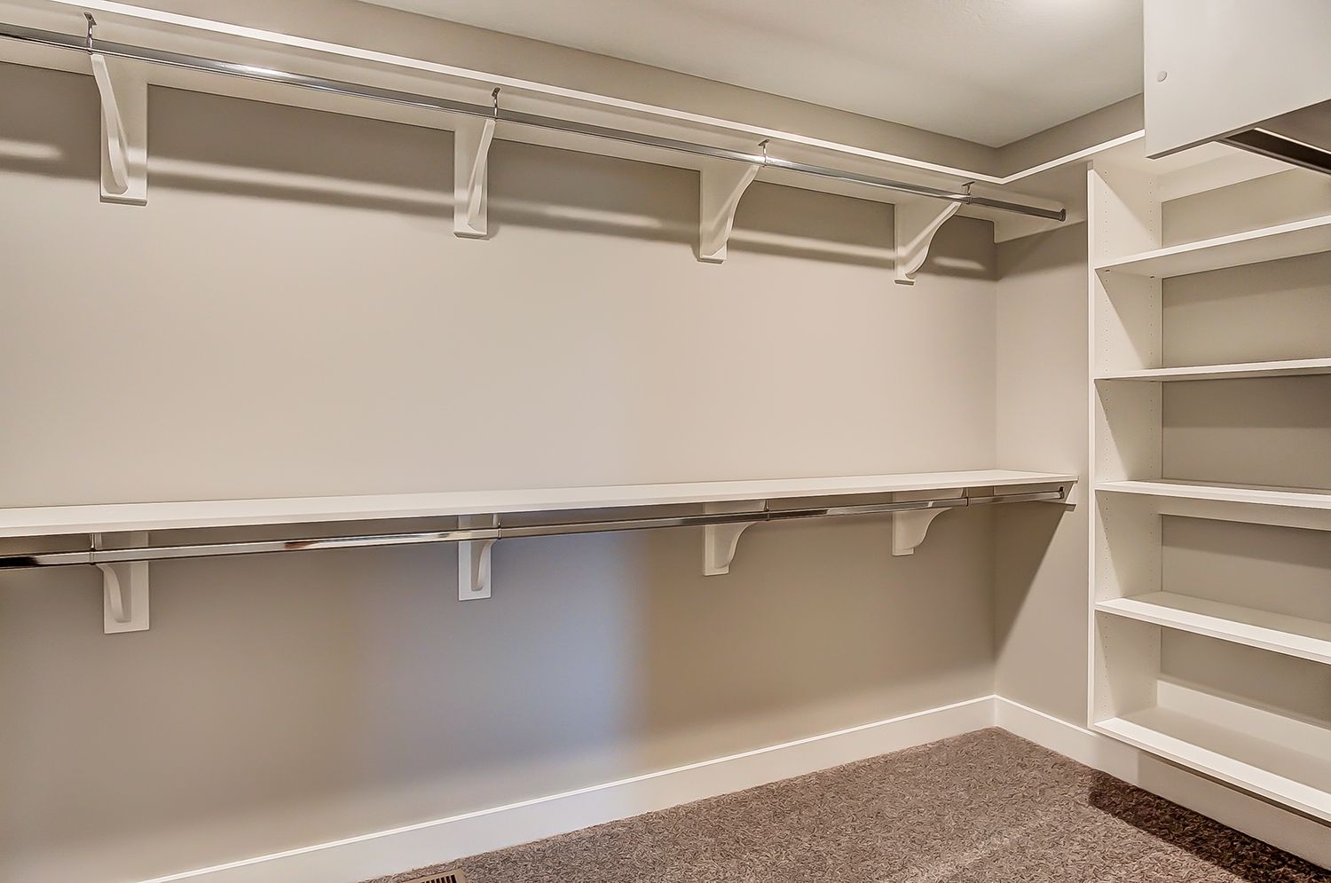 An empty walk in closet with lots of shelves and clothes racks.