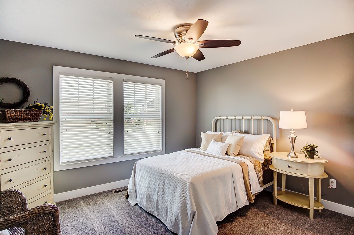 A bedroom with a bed , nightstand , dresser and ceiling fan.