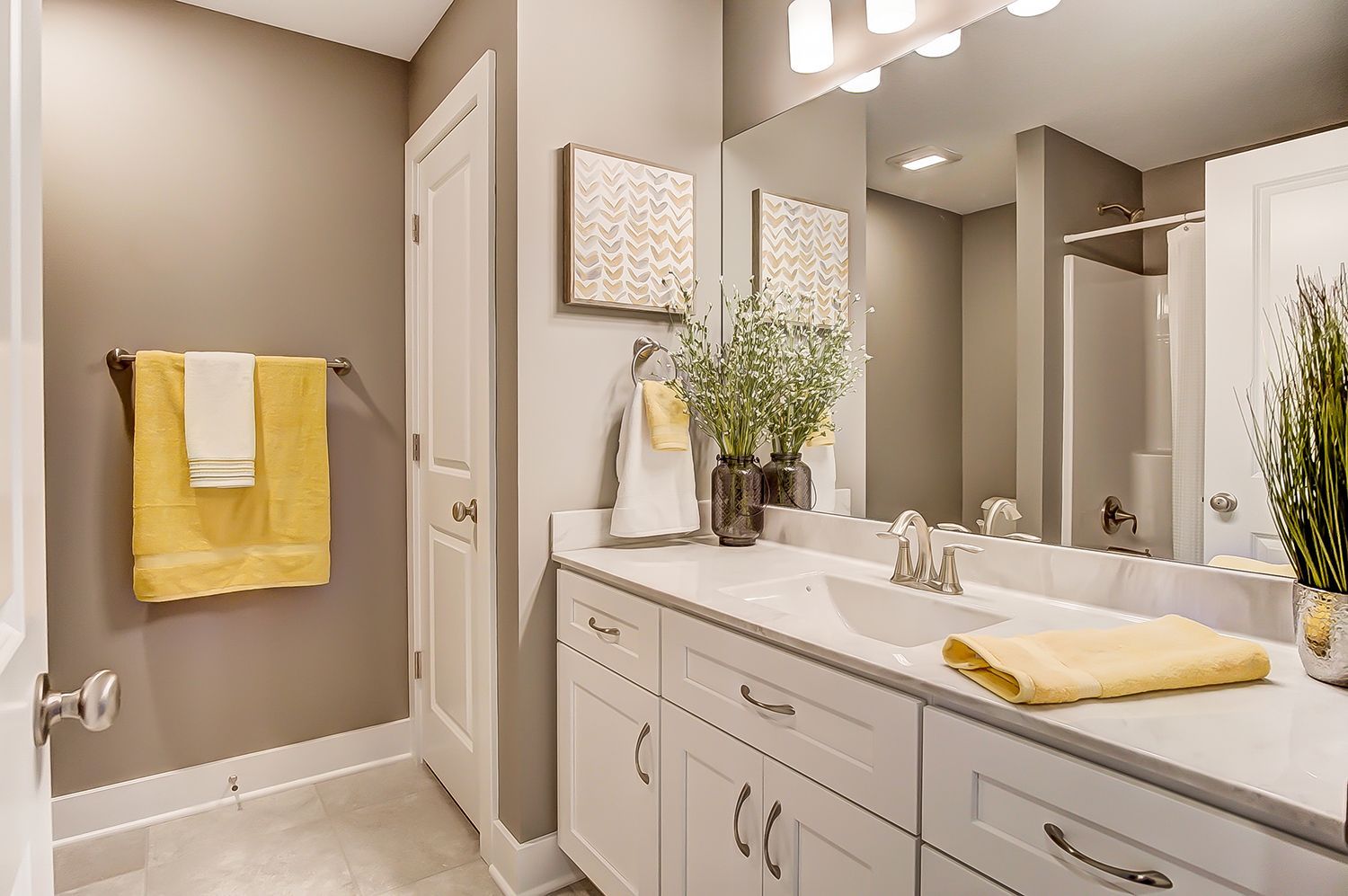 A bathroom with a sink , mirror and towels hanging on the wall.