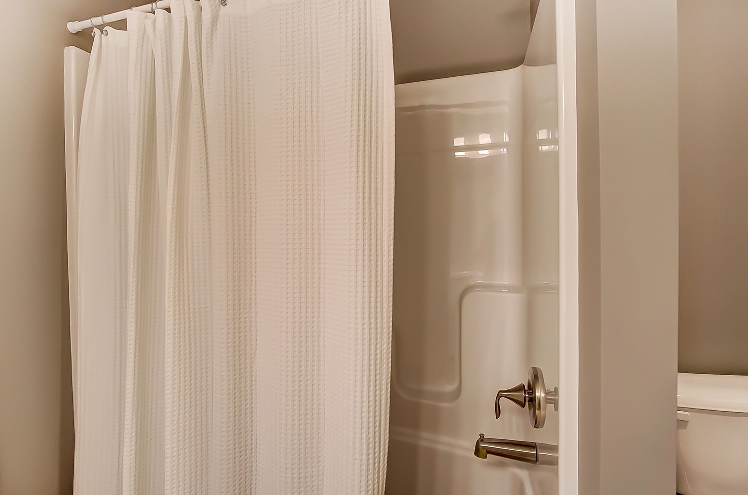 A bathroom with a shower curtain and a toilet.