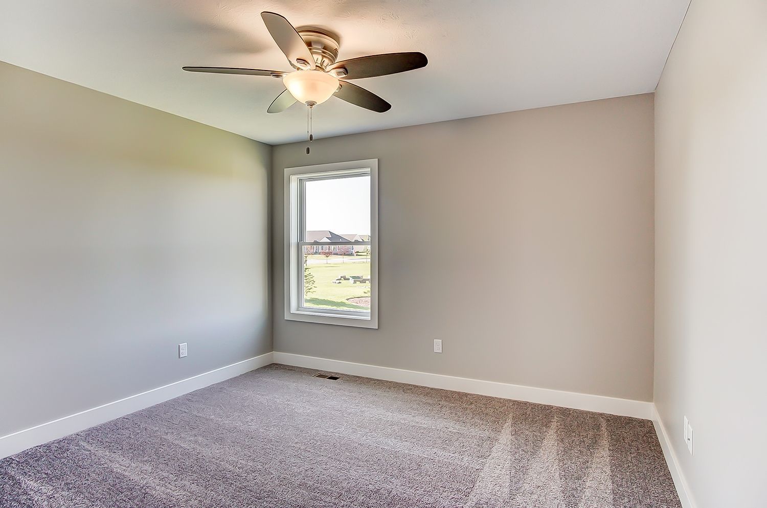 An empty bedroom with a ceiling fan and a window.