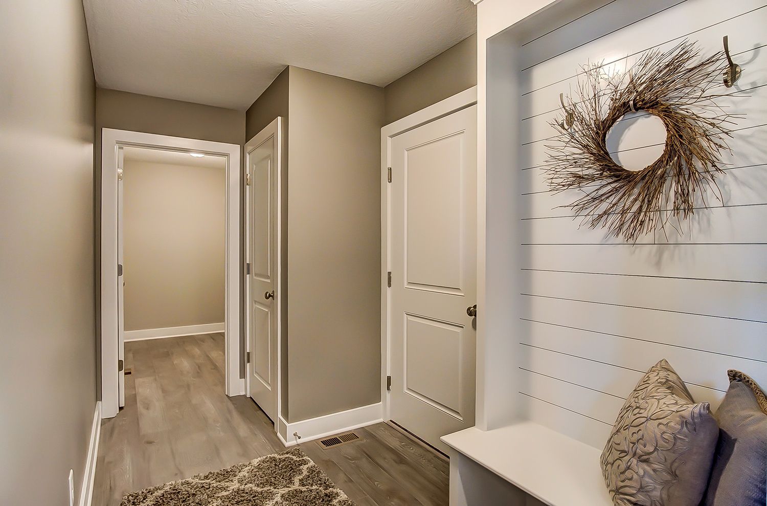 A hallway with a bench and a wreath on the wall.