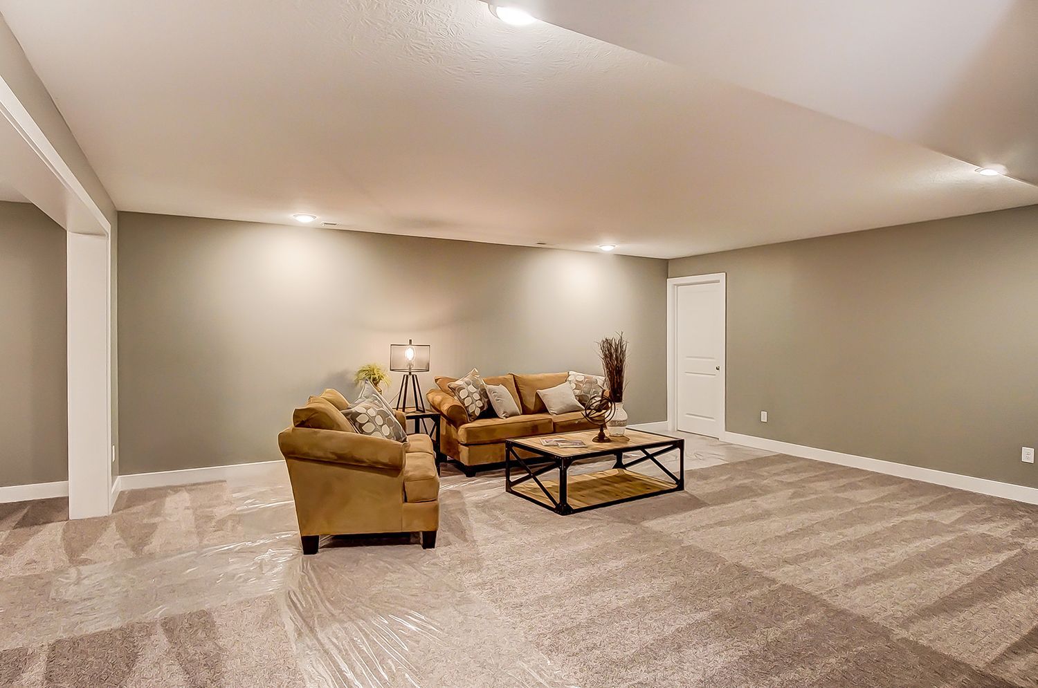 A living room in a basement with a couch , chair and coffee table.