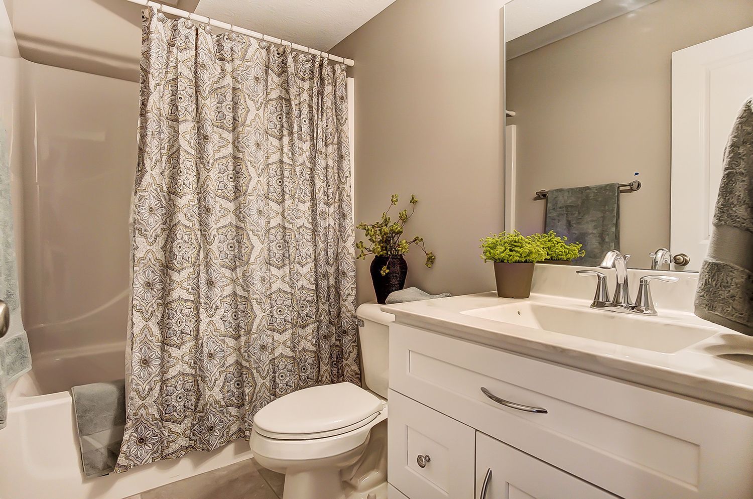 A bathroom with a toilet , sink , and shower curtain.