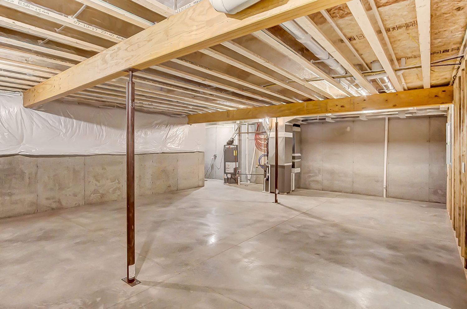 An empty basement with a wooden ceiling and concrete floor.