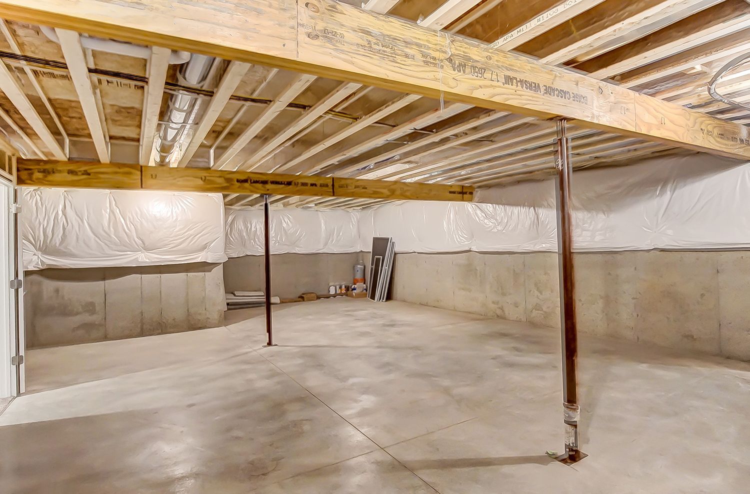 An empty basement with a wooden ceiling and concrete floor.