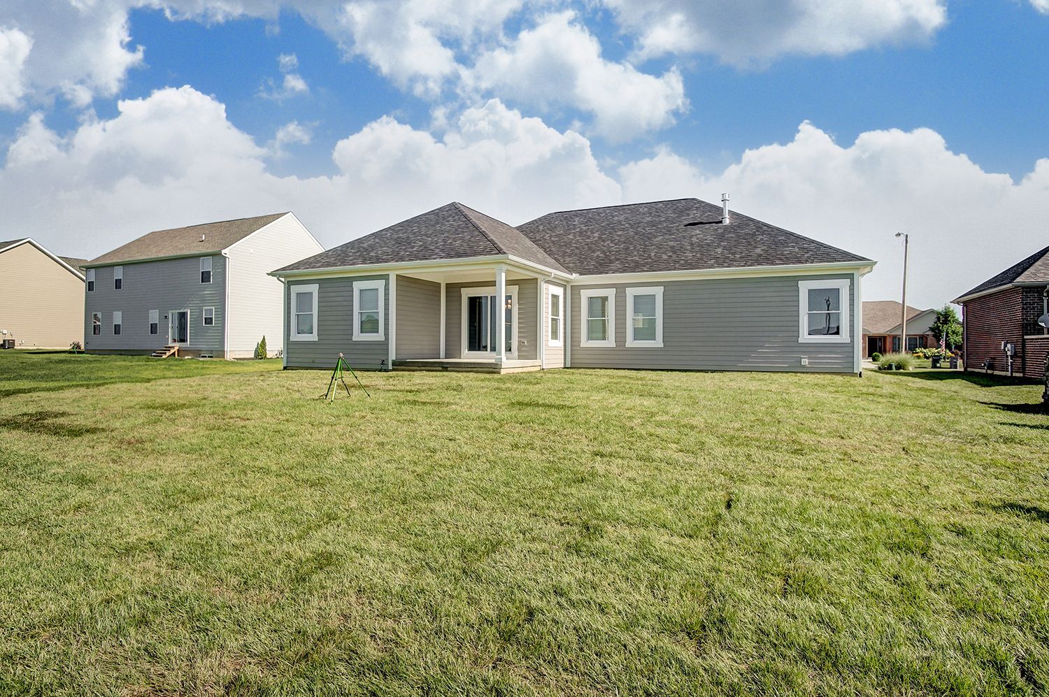 The back of a house with a large lawn in front of it.