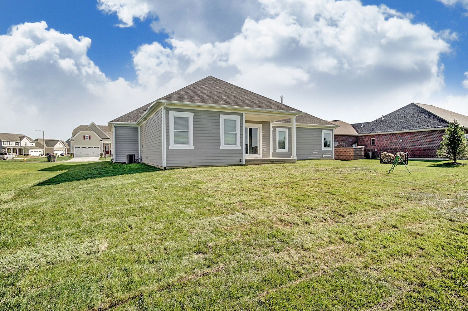 The back of a house with a large lawn in front of it.