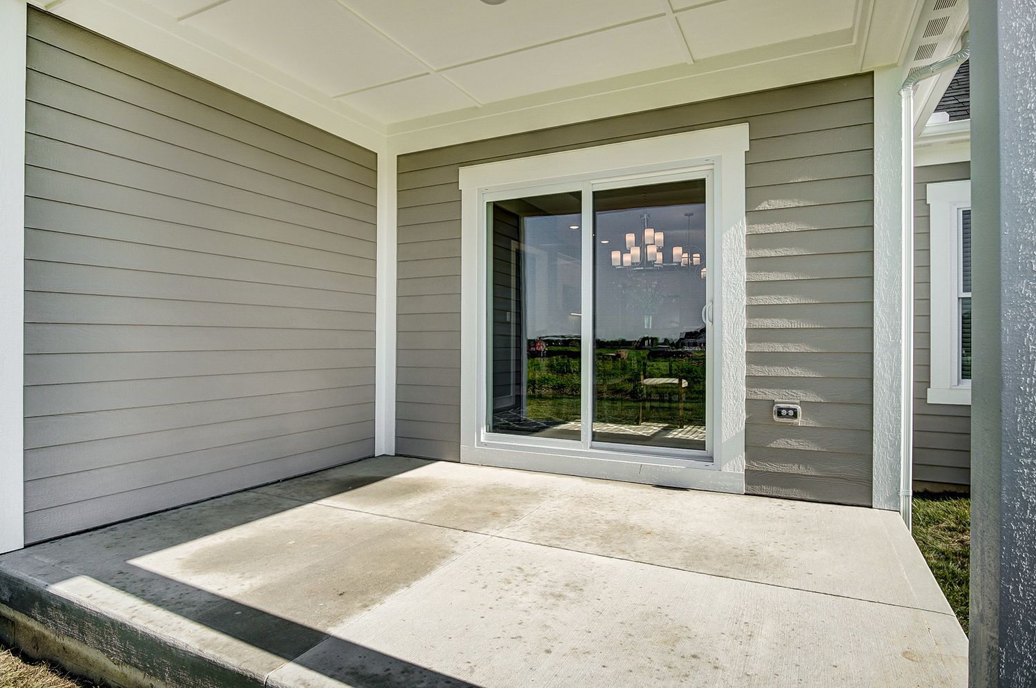 A patio with a sliding glass door on the side of a house.