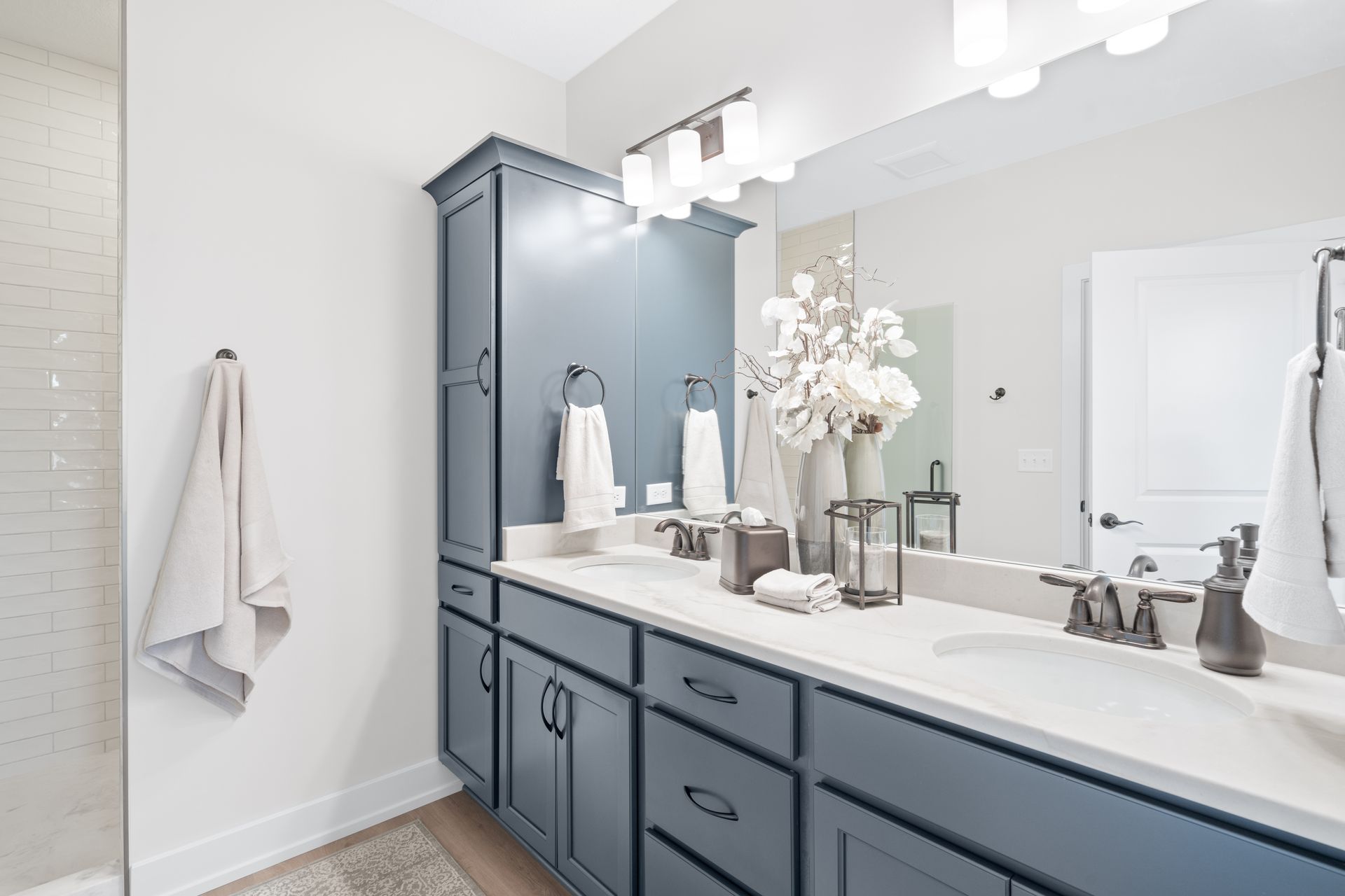 A bathroom with two sinks , a large mirror and a walk in shower.