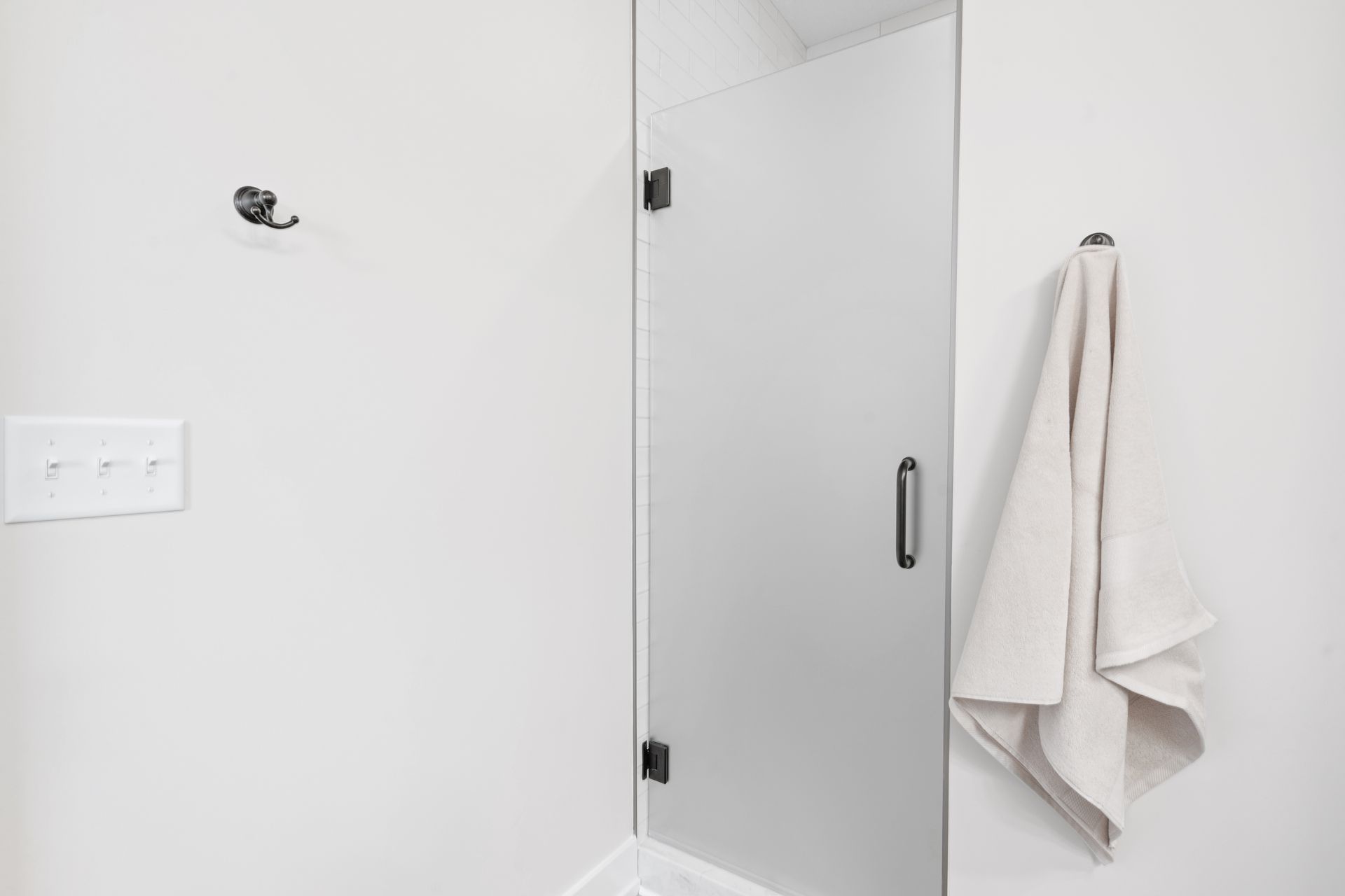A towel is hanging on a hook in a bathroom next to a shower door.