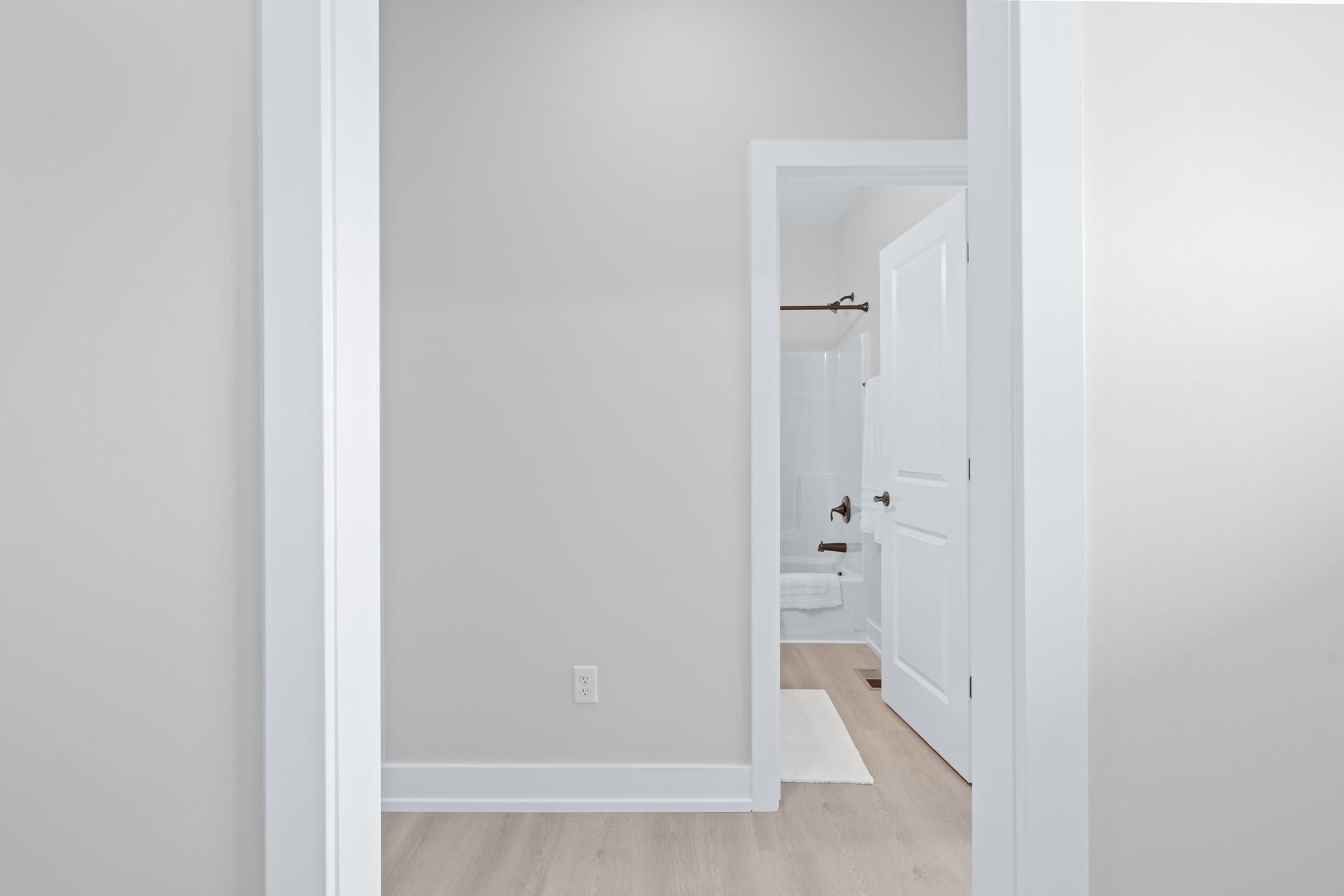 A hallway with a white door leading to a bathroom.