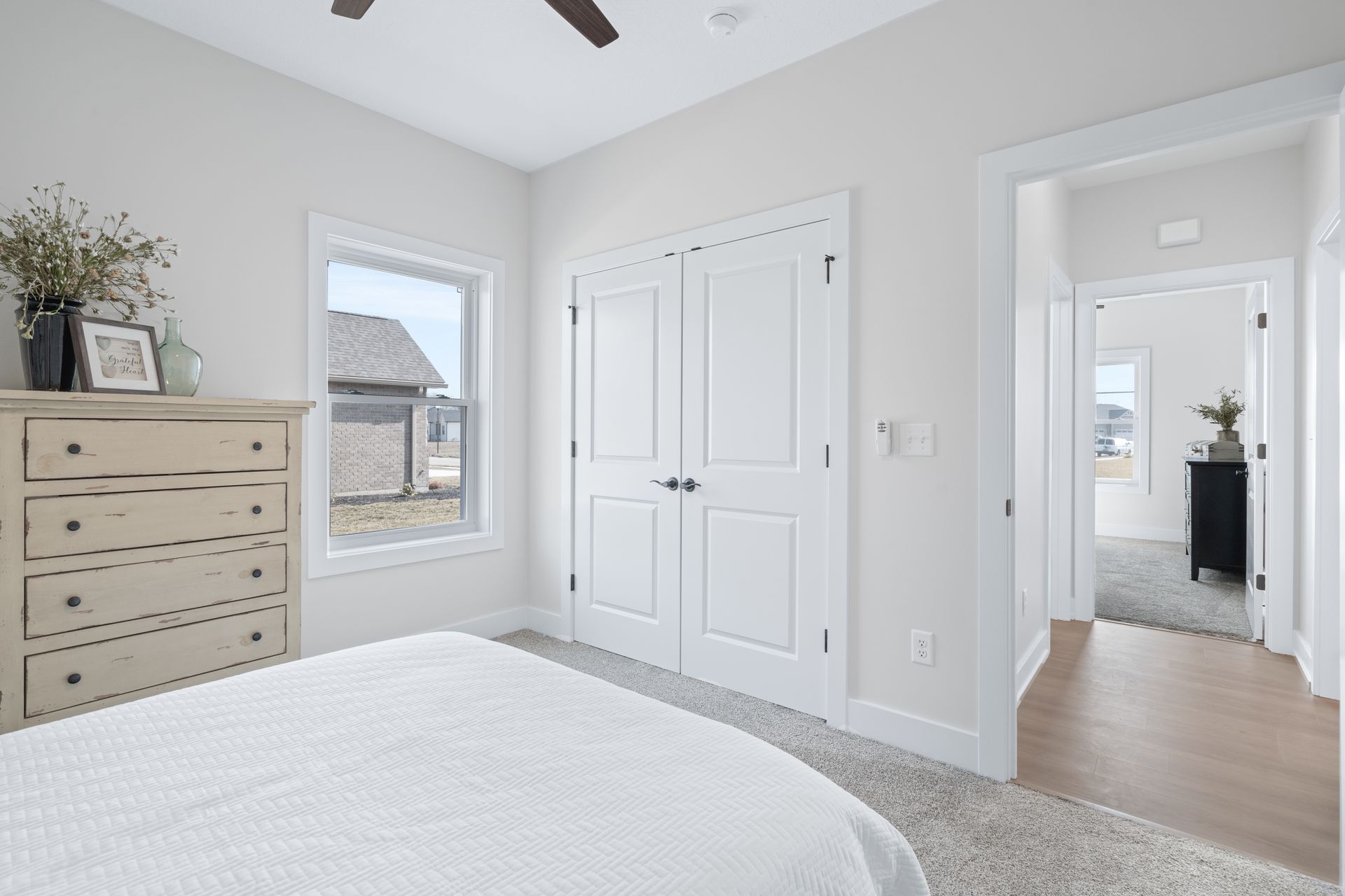 A bedroom with a bed , dresser , window and ceiling fan.