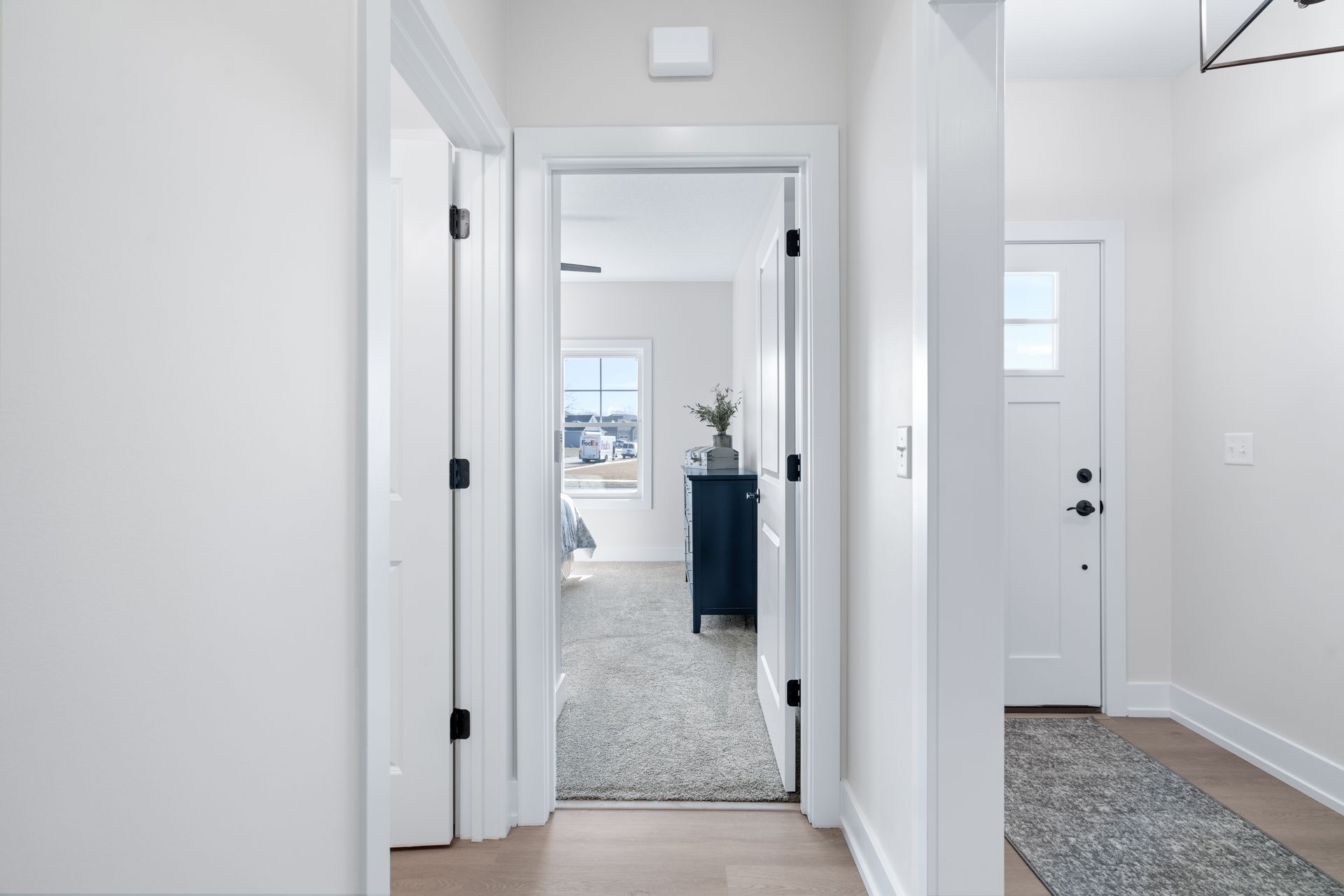 A hallway in a house with a door open leading to a bedroom.