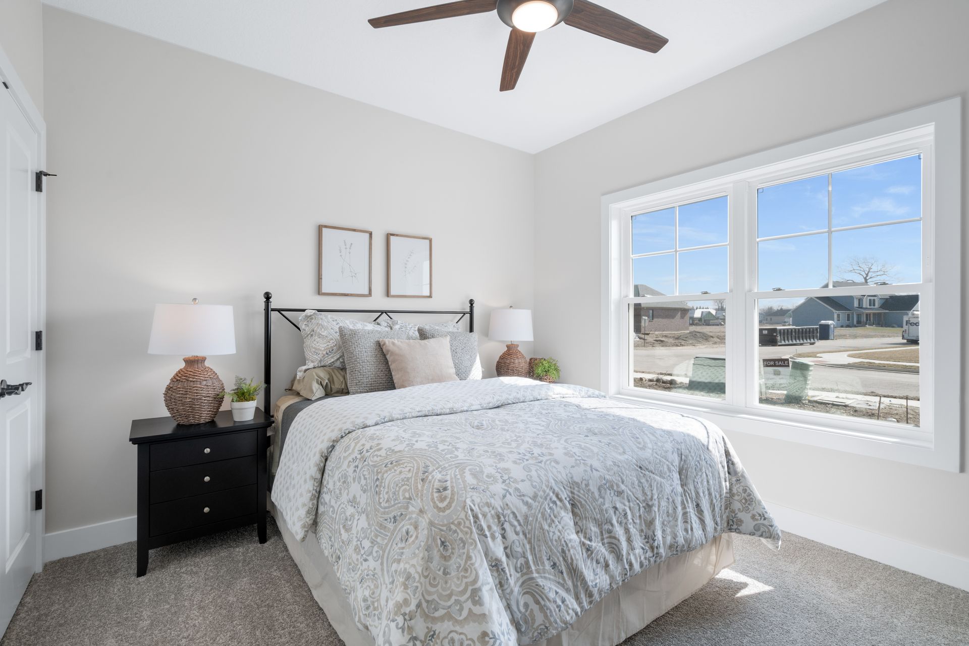 A bedroom with a bed , nightstand , lamps and a ceiling fan.