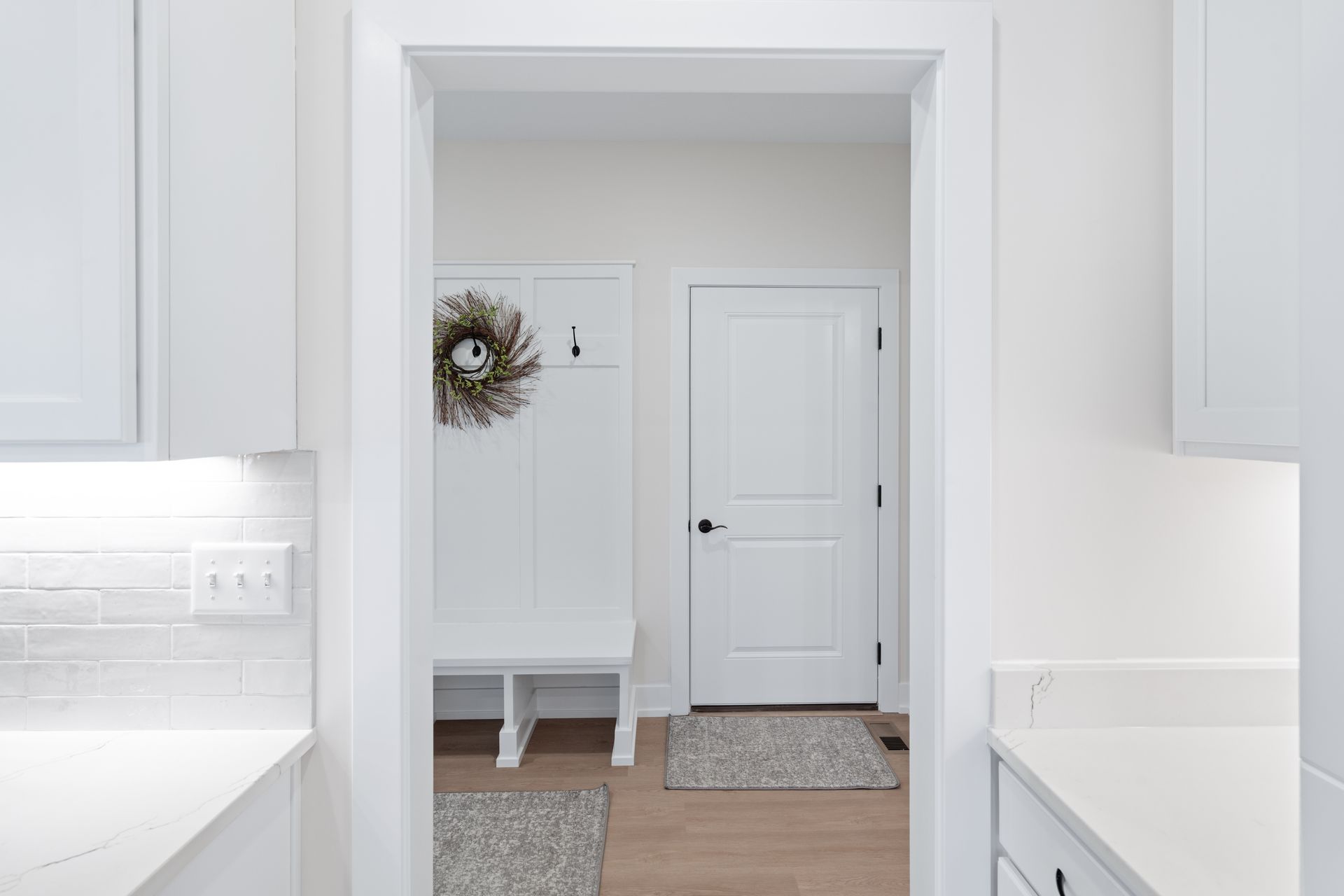 A kitchen with white cabinets and a white door leading to a hallway.