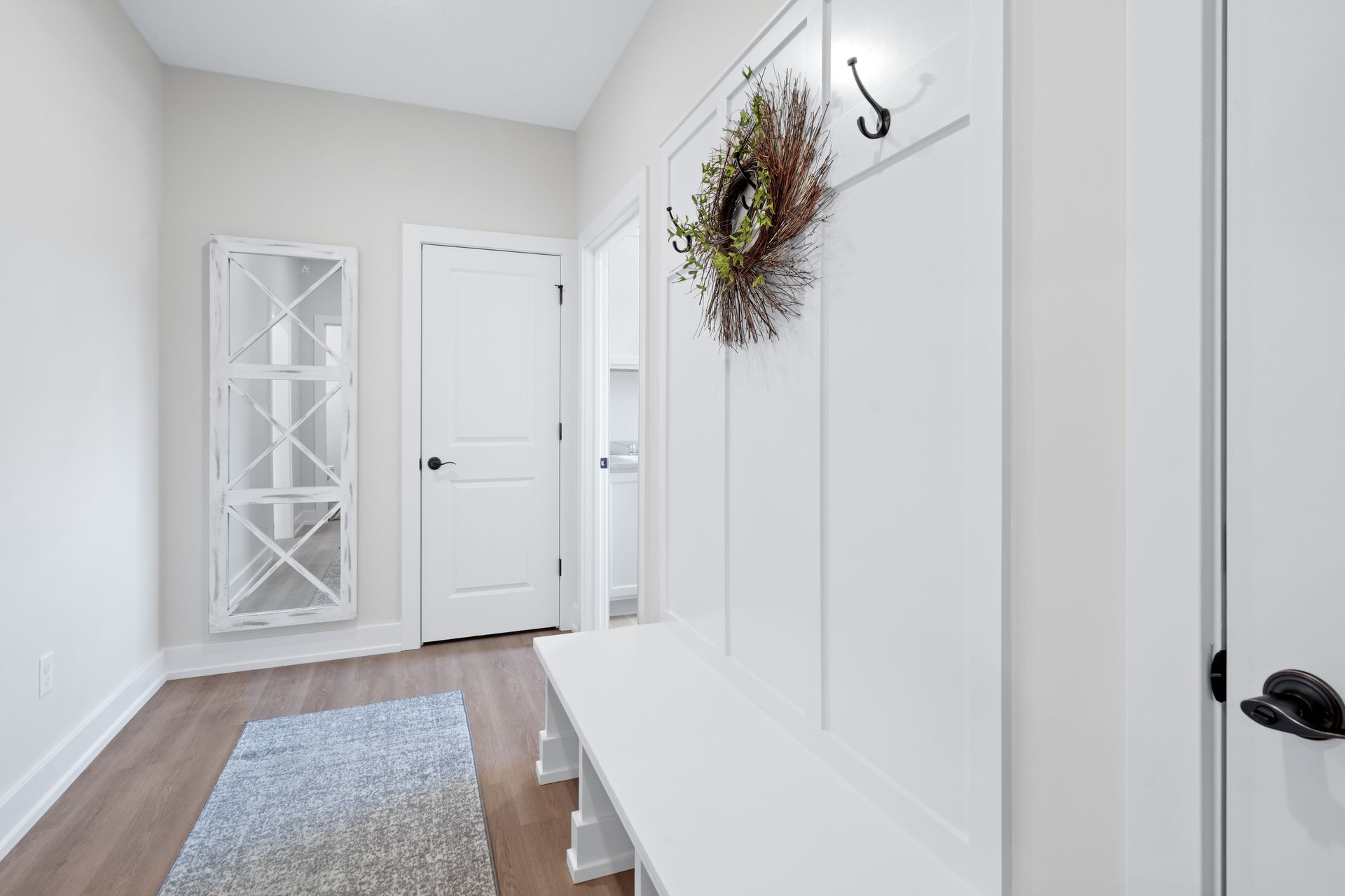 A hallway with a bench and a wreath on the wall.