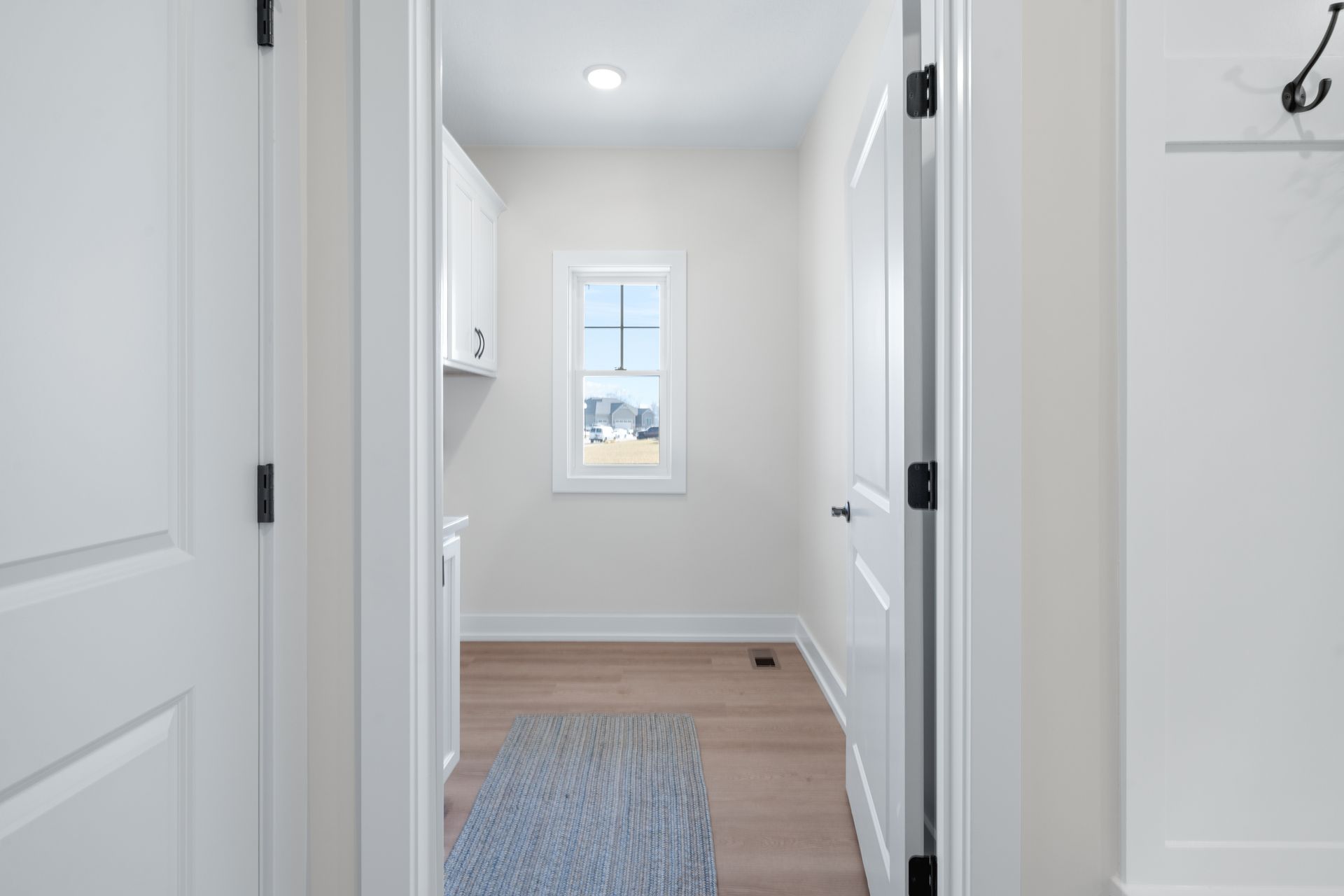 A hallway leading to a laundry room with a window.