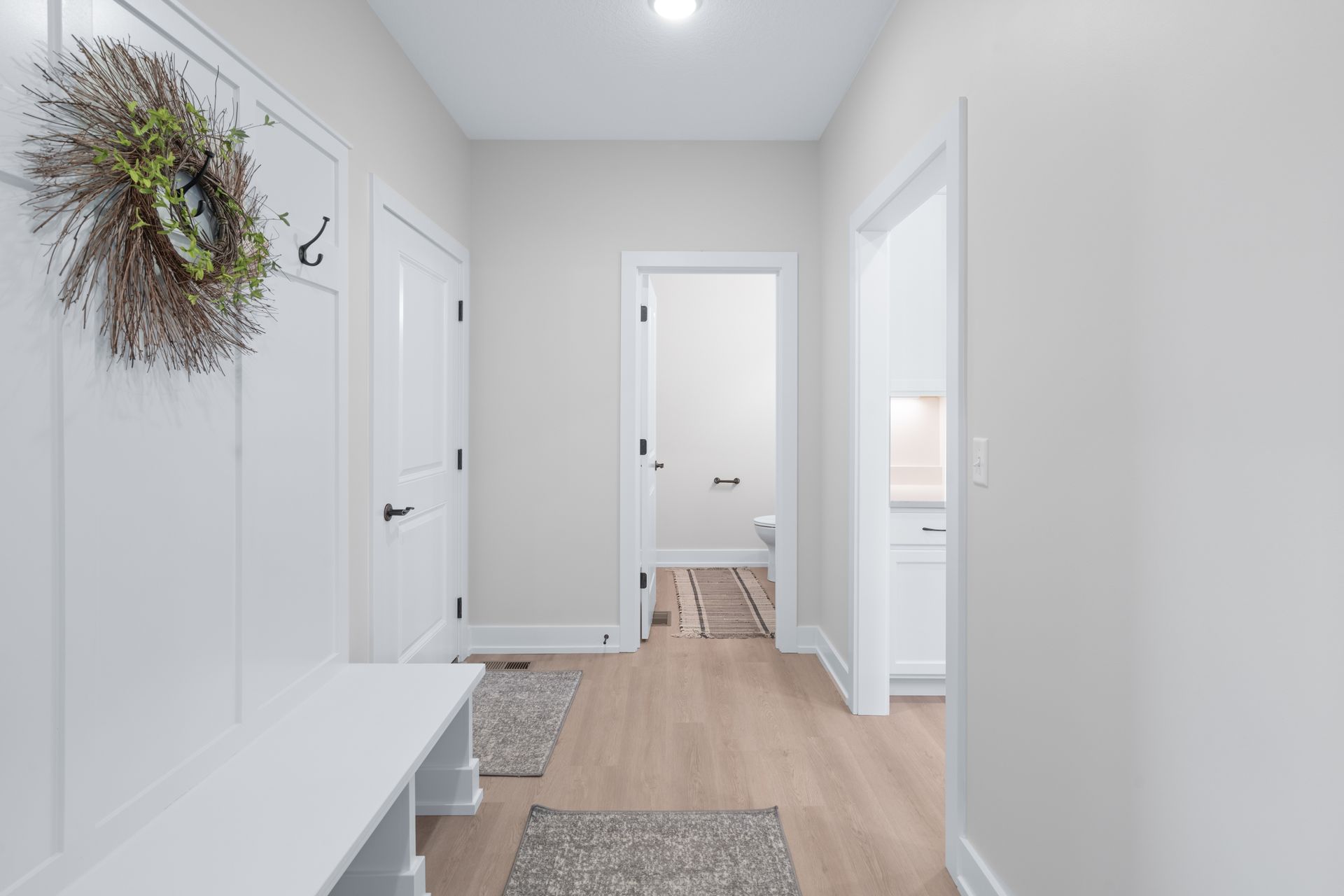 A hallway with a bench and a wreath on the door.