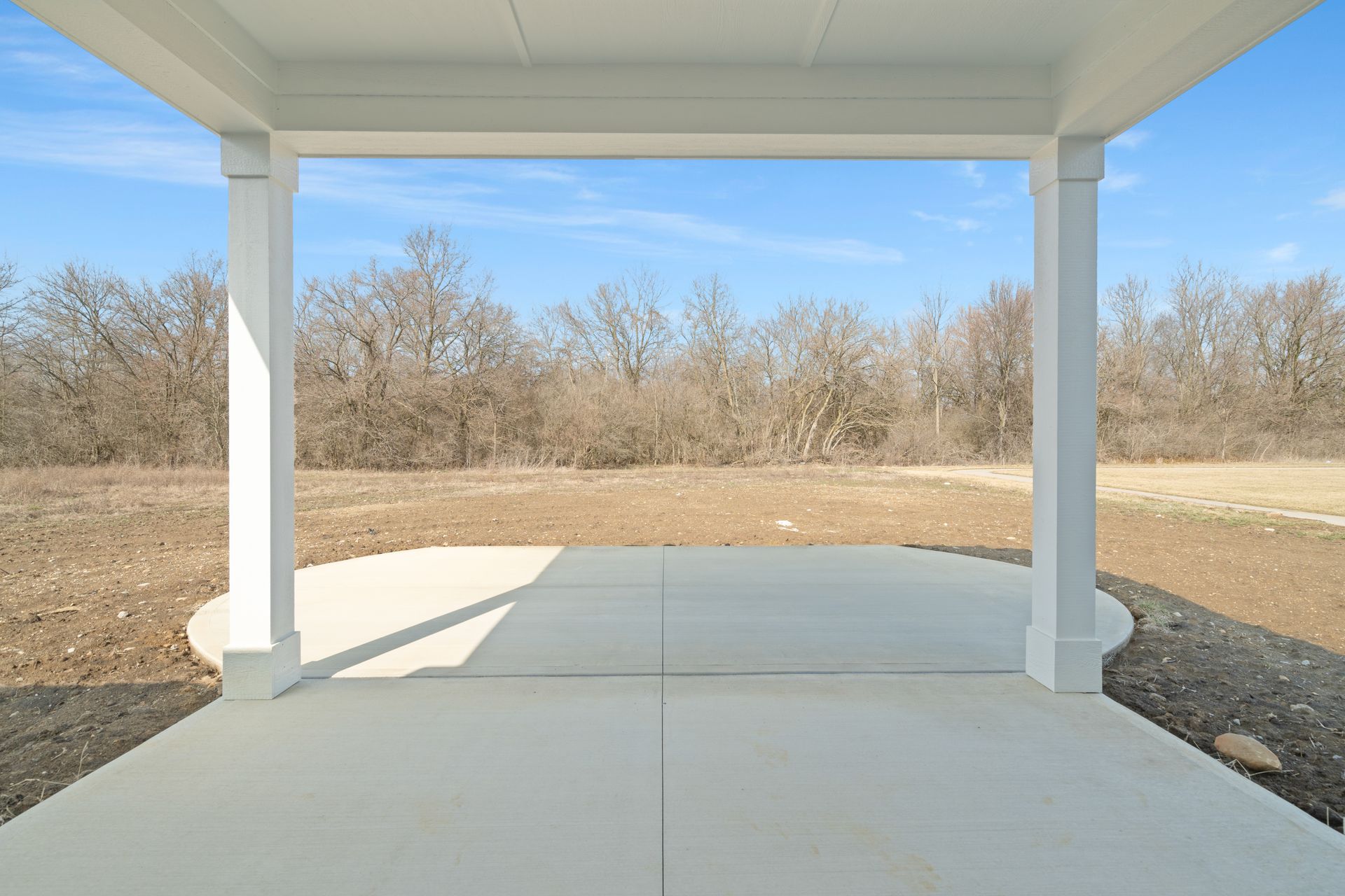 An empty patio with a view of a field and trees