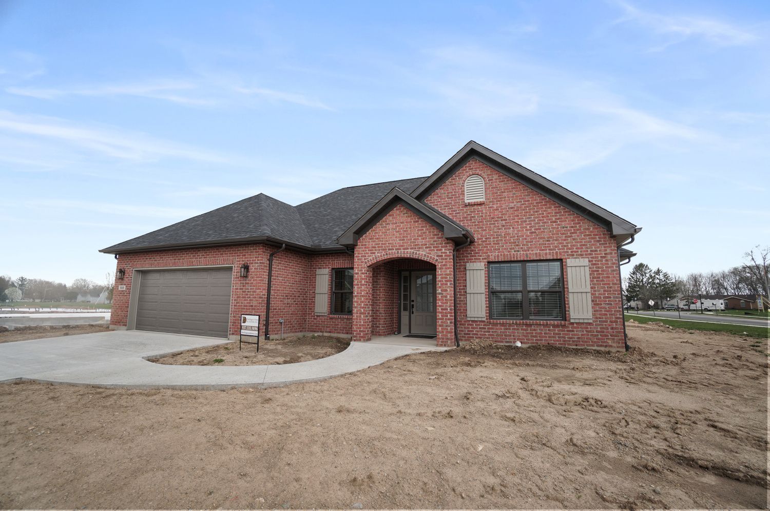 A brick house with a garage and a sign in front of it.