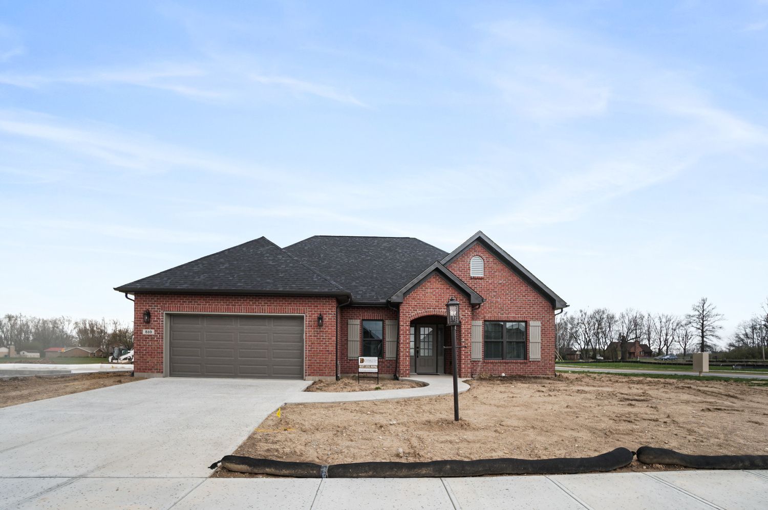 A brick house with a garage and a concrete driveway.