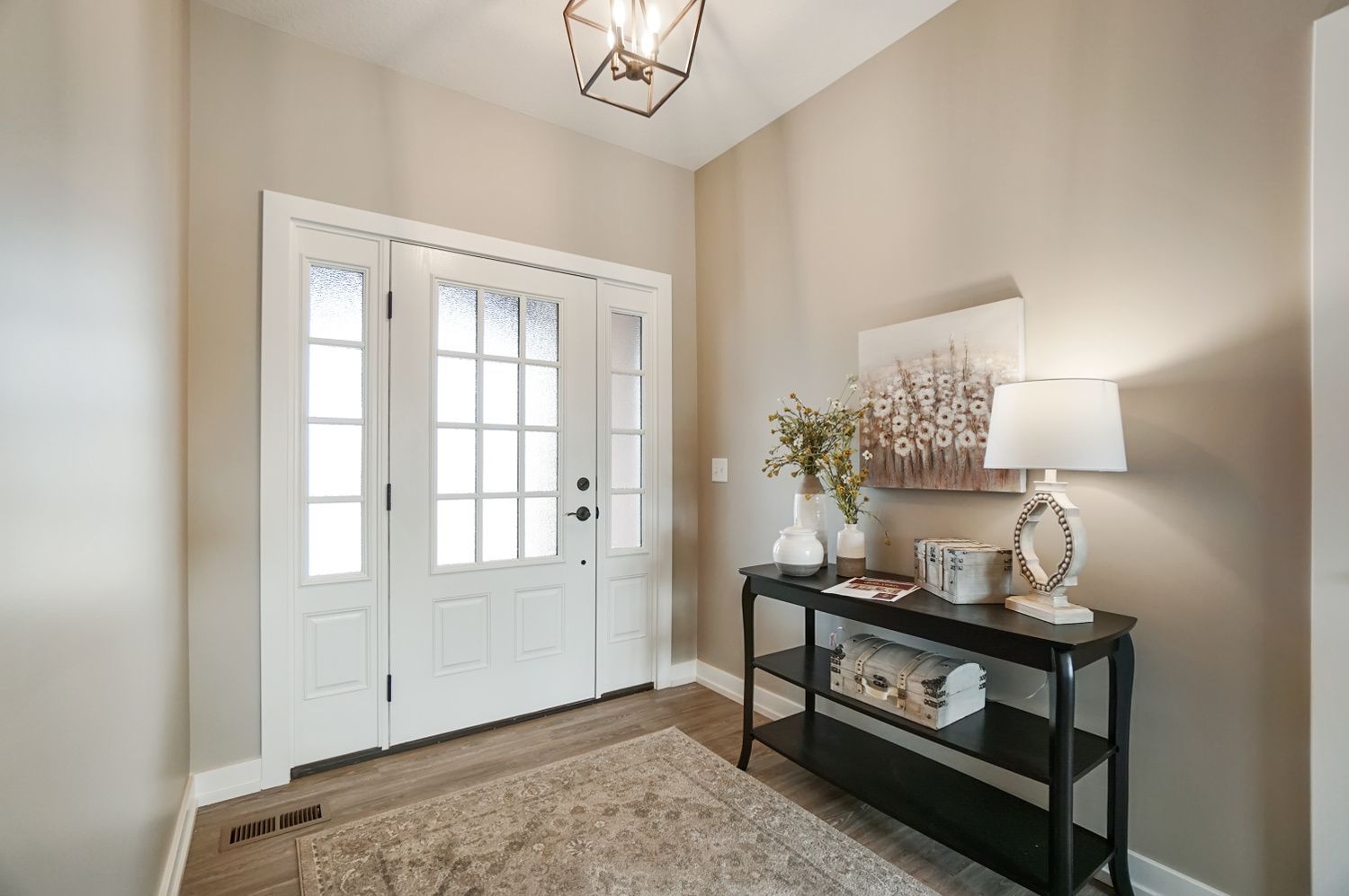 A hallway with a table and lamps in front of a door.