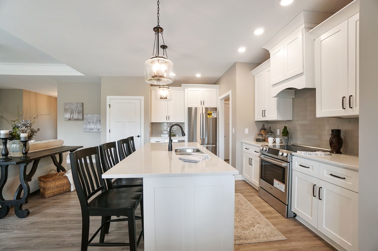A kitchen with white cabinets , stainless steel appliances , and a large island.