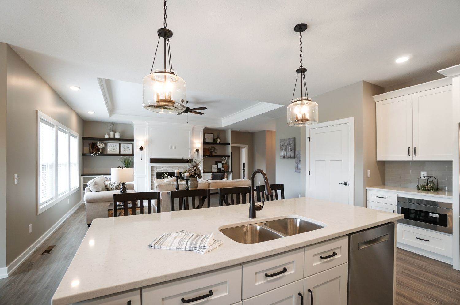 A kitchen with white cabinets , a sink , a dishwasher and a ceiling fan.