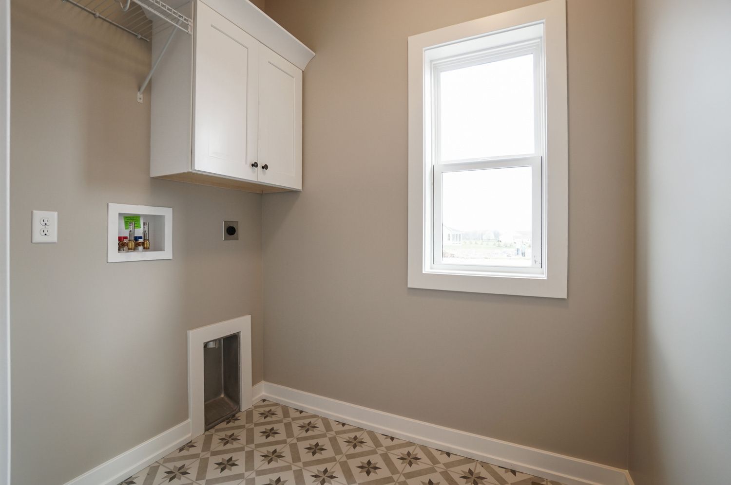 A laundry room with a dog door and a window.